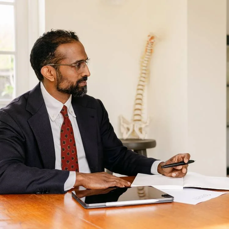 Mr Ahilan Kailaya-Vasan, neurosurgeon, looking at patient information