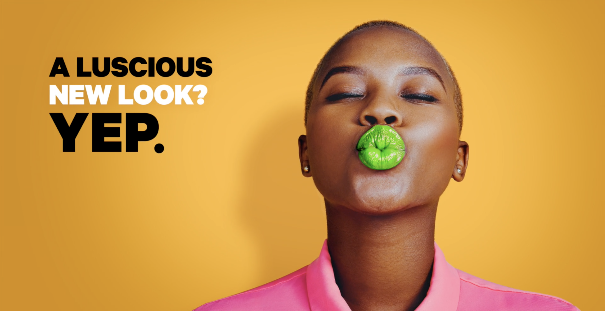 A person in a black hoodie with a backpack standing on a subway platform, looking down with a neutral expression, with train lights approaching in the background.
