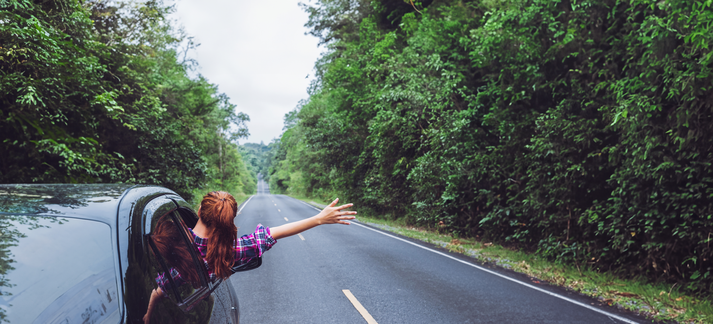 Woman with arm out the window driving down a country road in Ontario