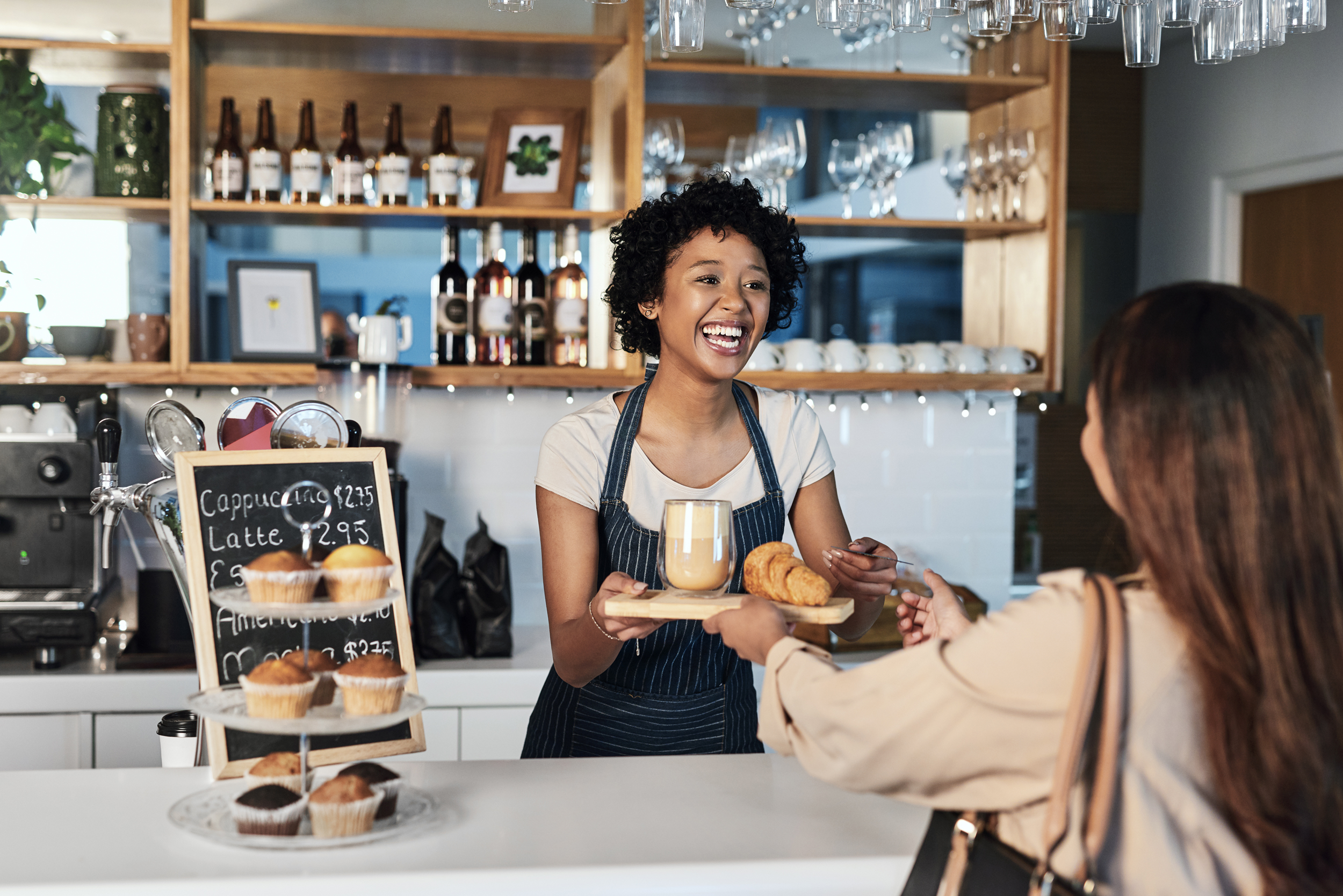 Black woman smiling in small business restaurant helping client at checkout