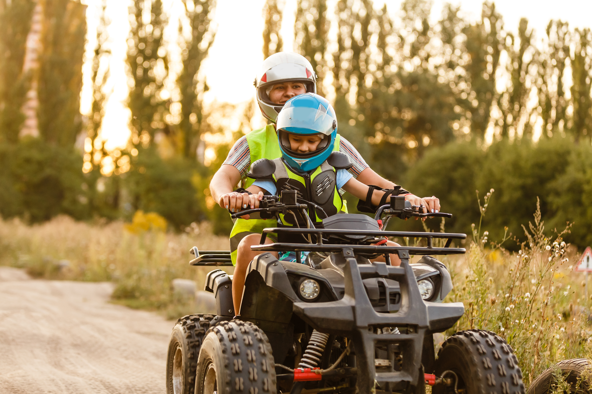 little boy with instructor on ATV in nature on a trail