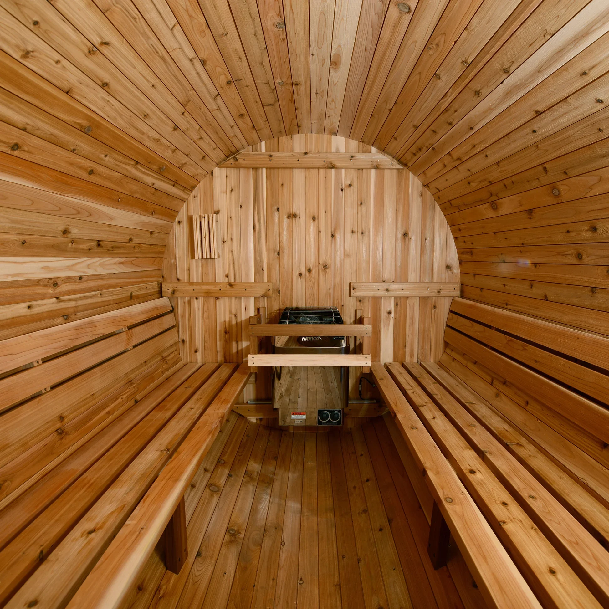 Interior of a dry sauna with wooden benches along both sides and a stove at the back.