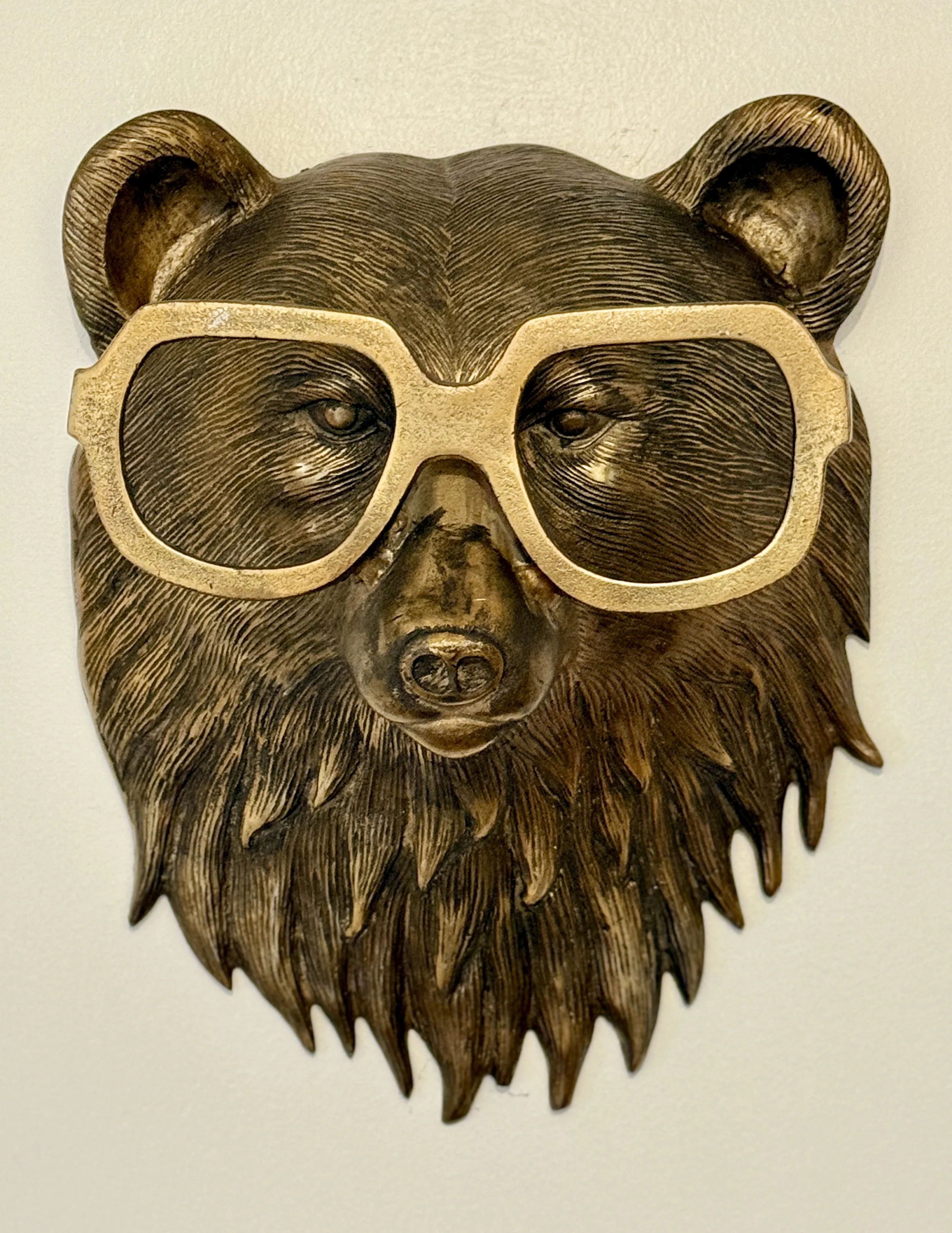 Wooden bear head wall decor with glasses.
