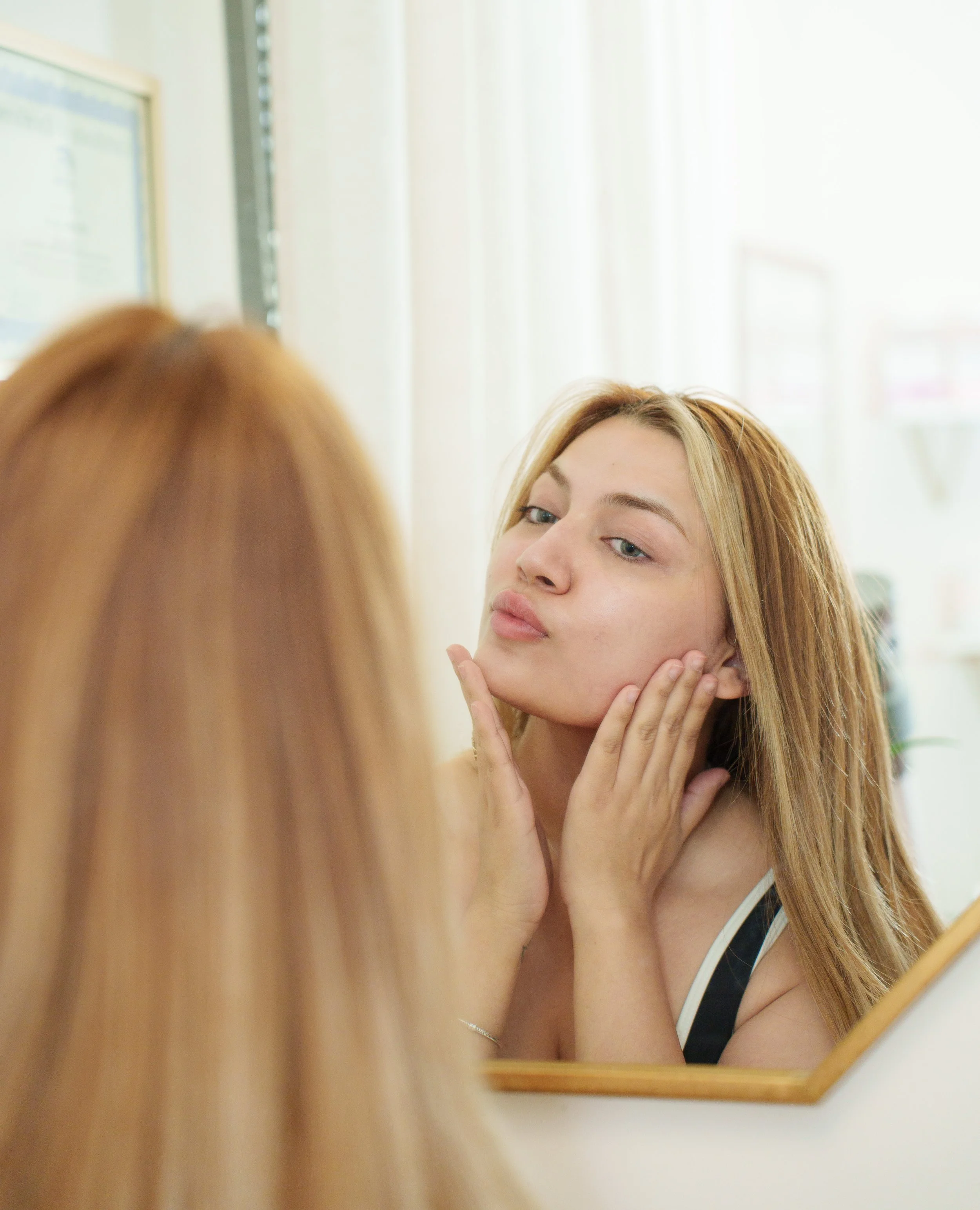 Beauty salon display with skincare products, gold decorative accents, a candle, and a business card for Skin by Oksana on a tray.