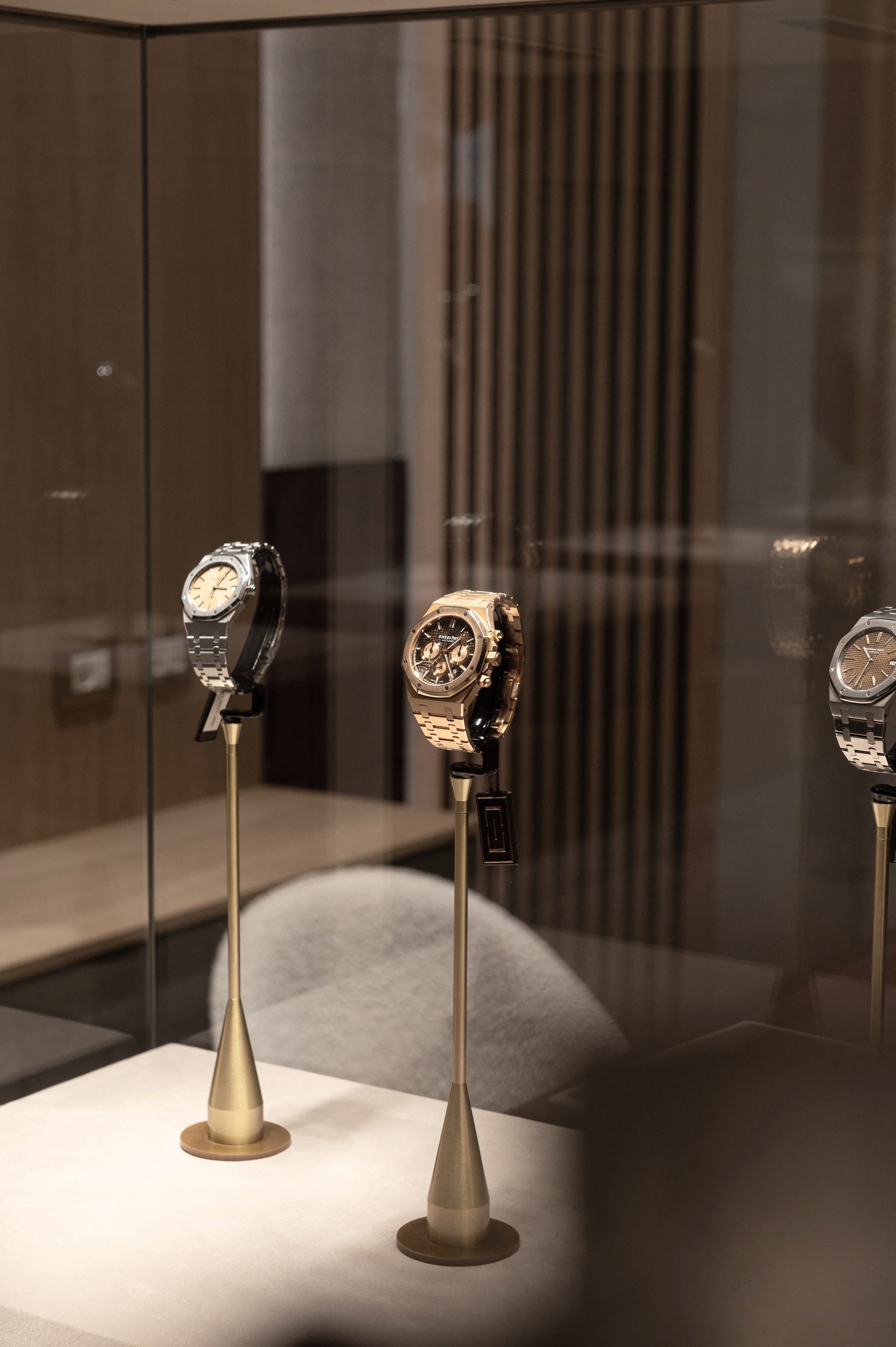 Costantini Watches Brand Identity by Define London - Watches & Jewellery, Three luxury watches displayed on gold stands in a glass case.