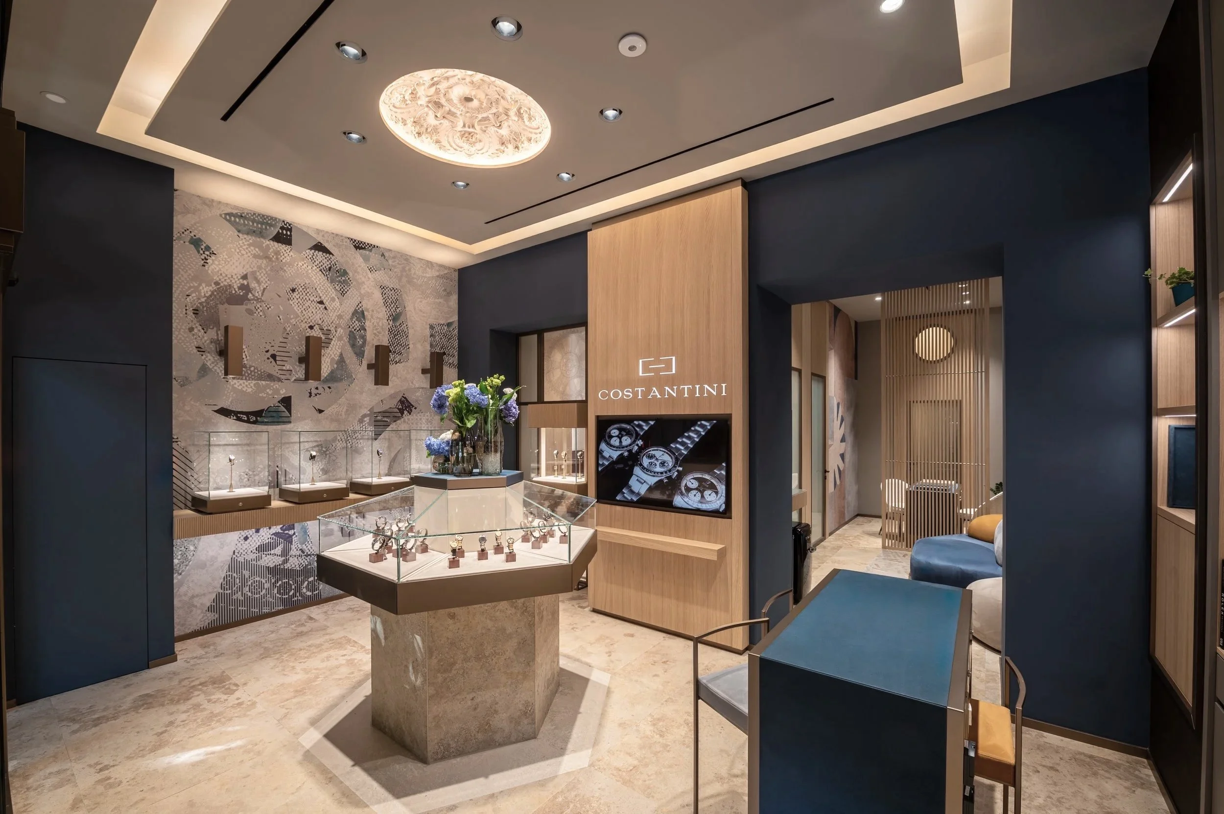 Costantini Watches Brand Identity by Define London - Watches & Jewellery, Interior of a jewelry store with display cases, decorative wall art, and a sign reading 'COSTANTINI' showcasing watches.