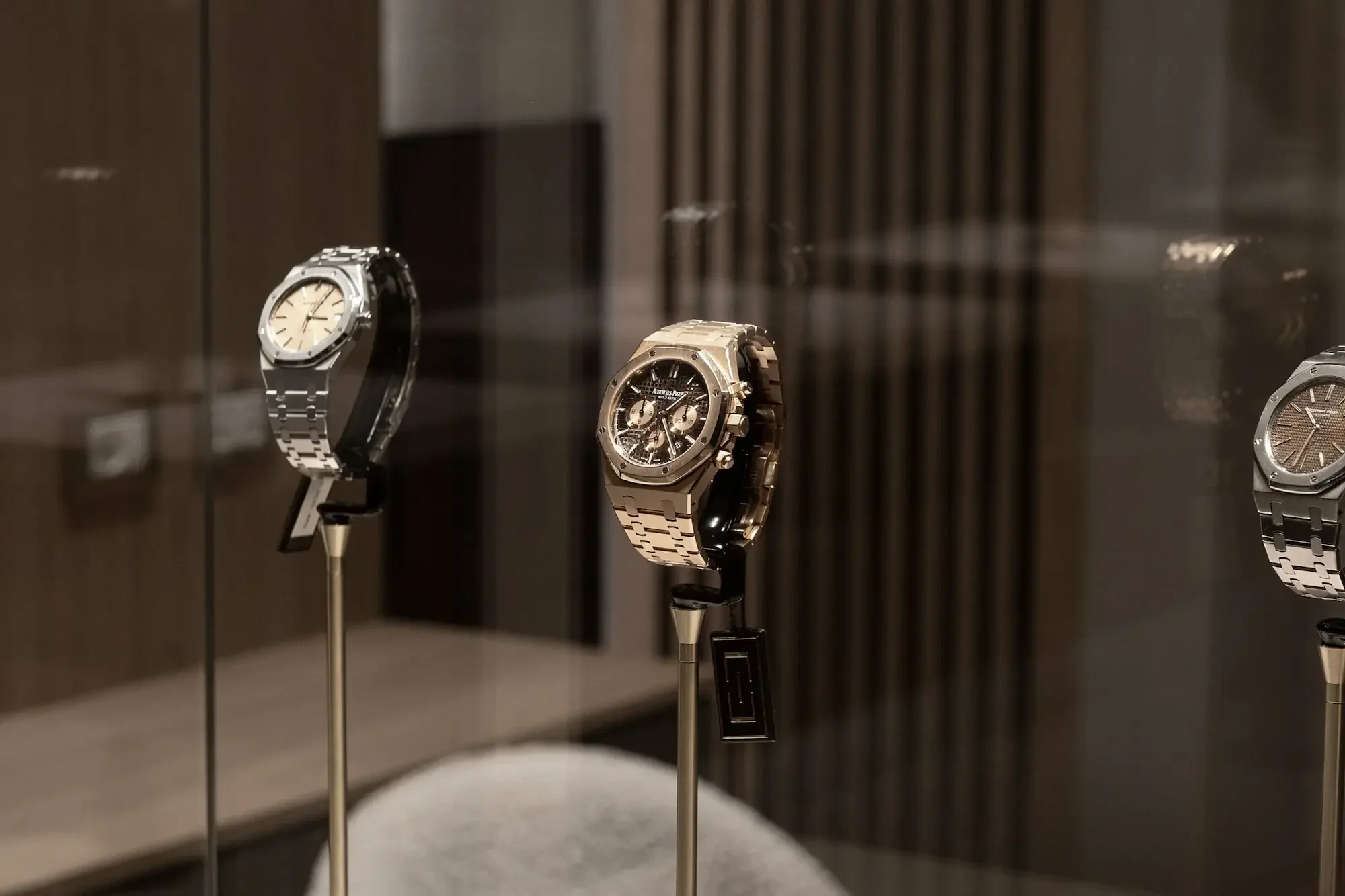 Display of luxury watches in a glass case with spotlights on each watch.
