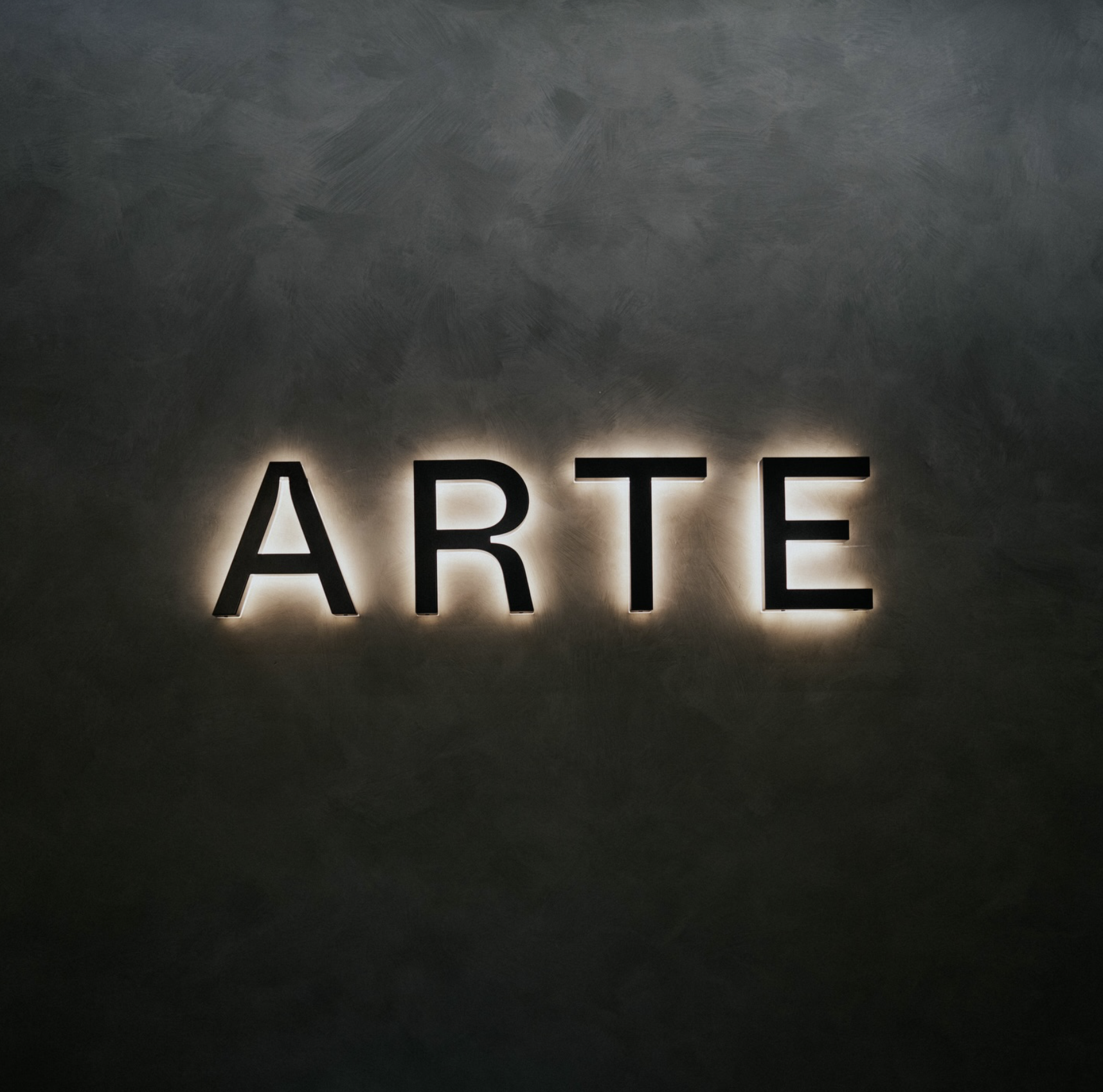 Arte Dental brand identity by Define London - Illuminated Logo spelling out the word 'ARTE' in black letters against a dark background.