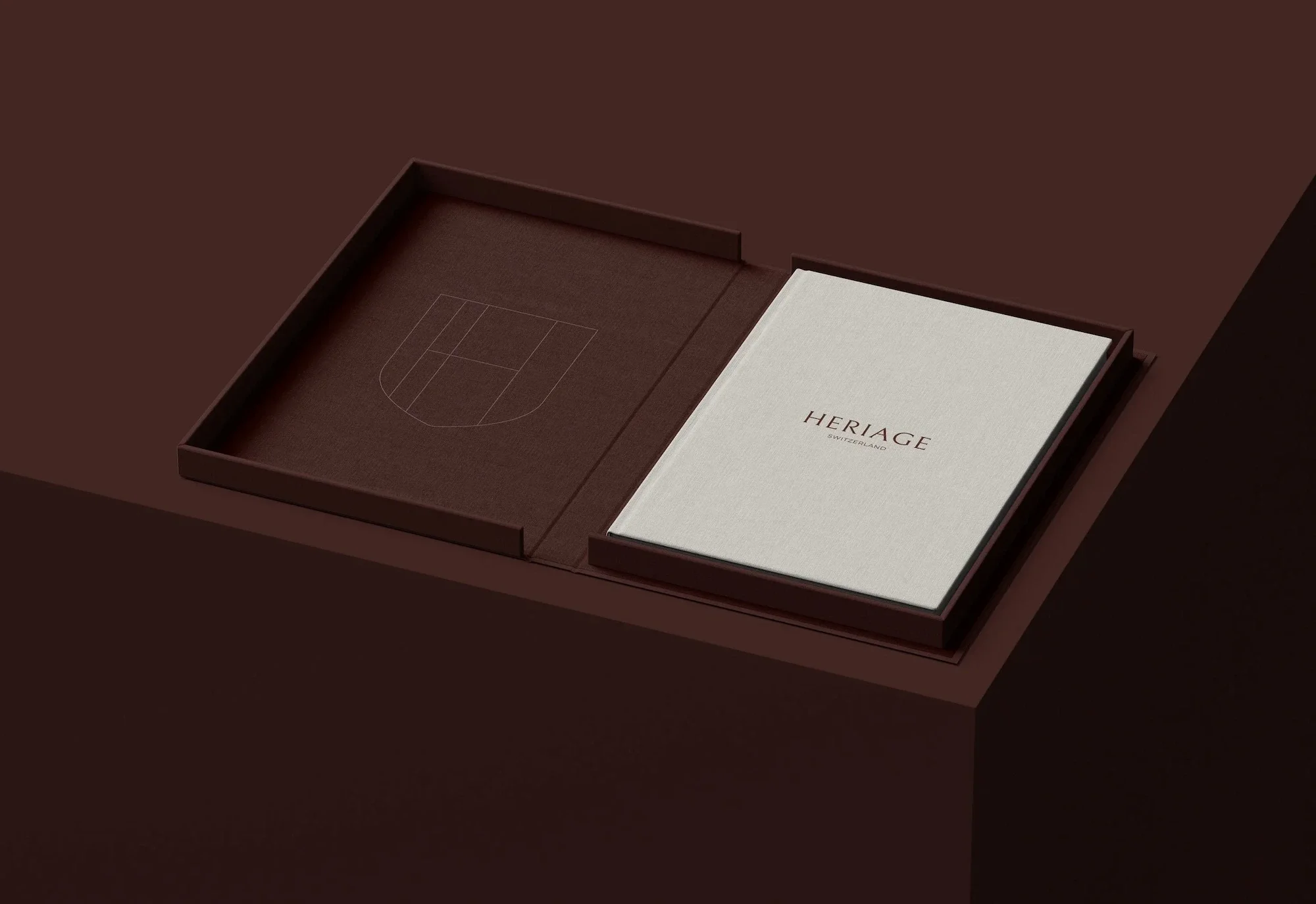 A dark brown open box with a white card inside that reads 'HERIAGE SWITZERLAND' on a matching brown background.