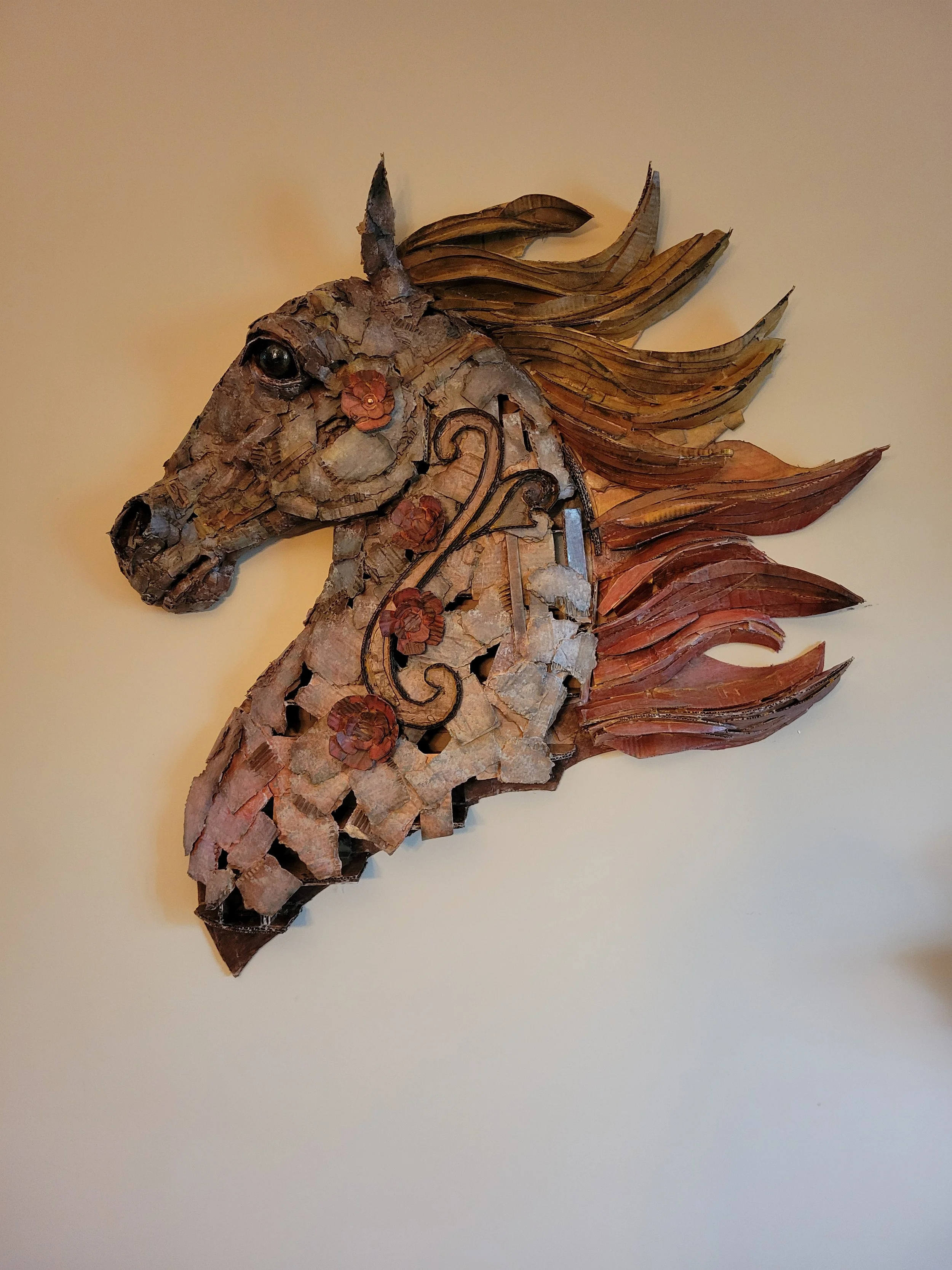 A wall decoration of a horse's head made from various pieces of cardboard.
