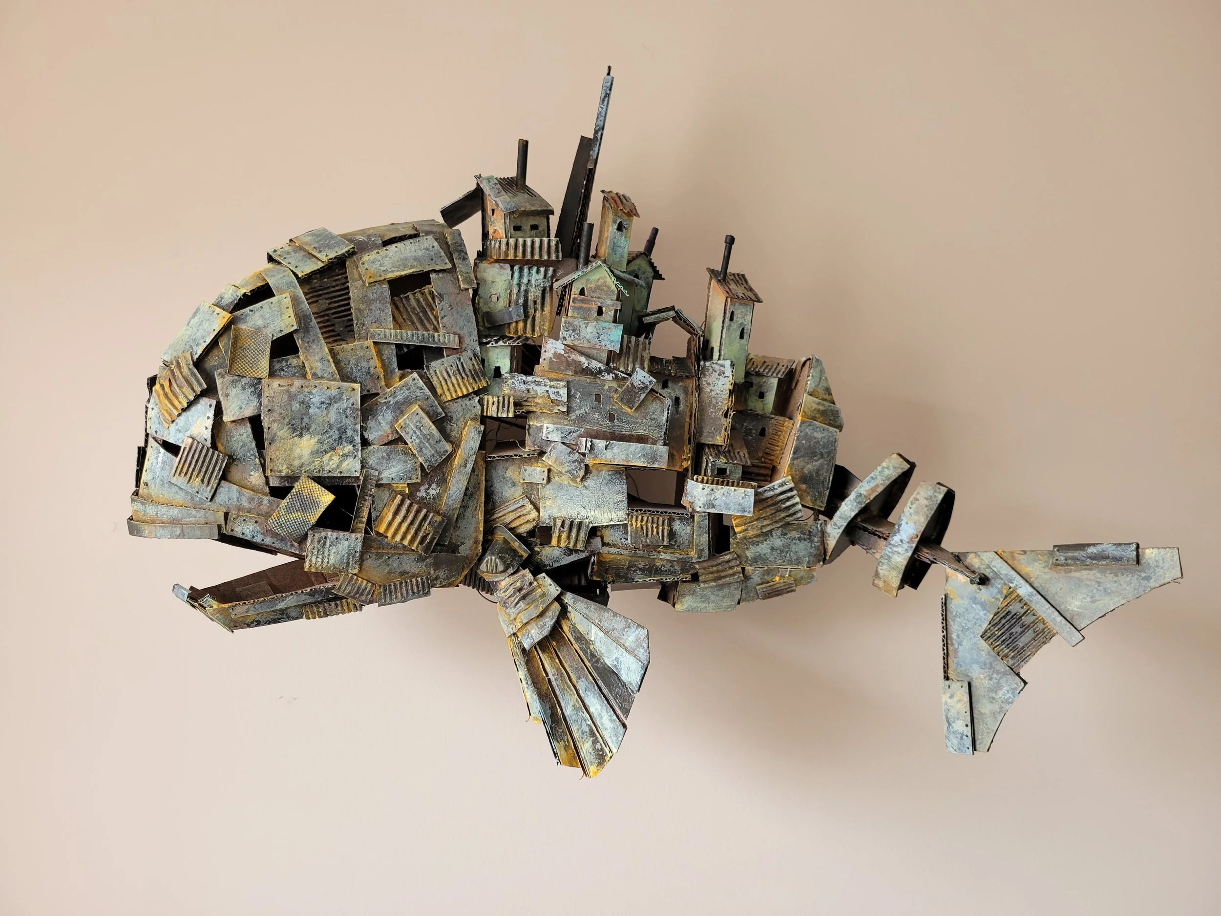 Metal sculpture of a fish made from recycled cardboard and scrap.