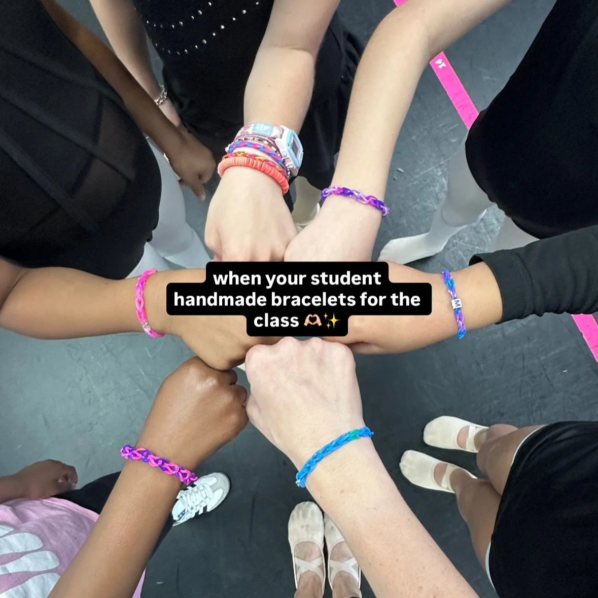 Multiple students with different skin tones show their colorful handmade bracelets joined together in a circle, symbolizing unity and teamwork in the classroom.
