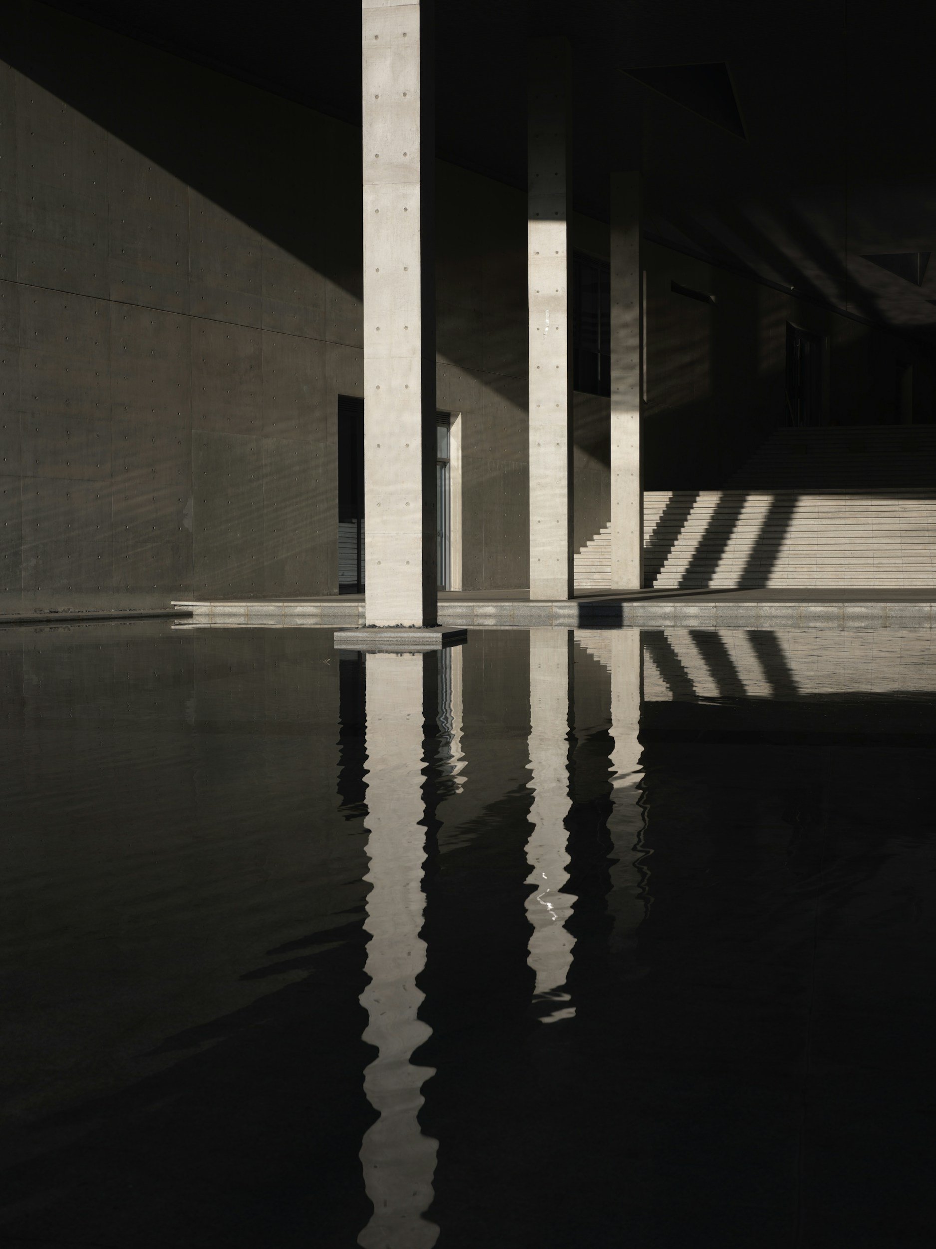 Modern financial district architecture with symmetrical concrete columns and reflective water, representing stability, structure, and long-term wealth preservation.