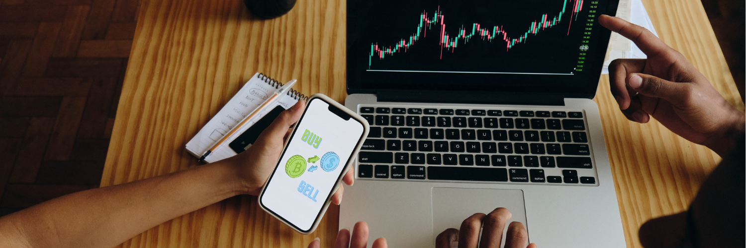 Computer with stock exchange and "buy or sell" on a cellphone screen