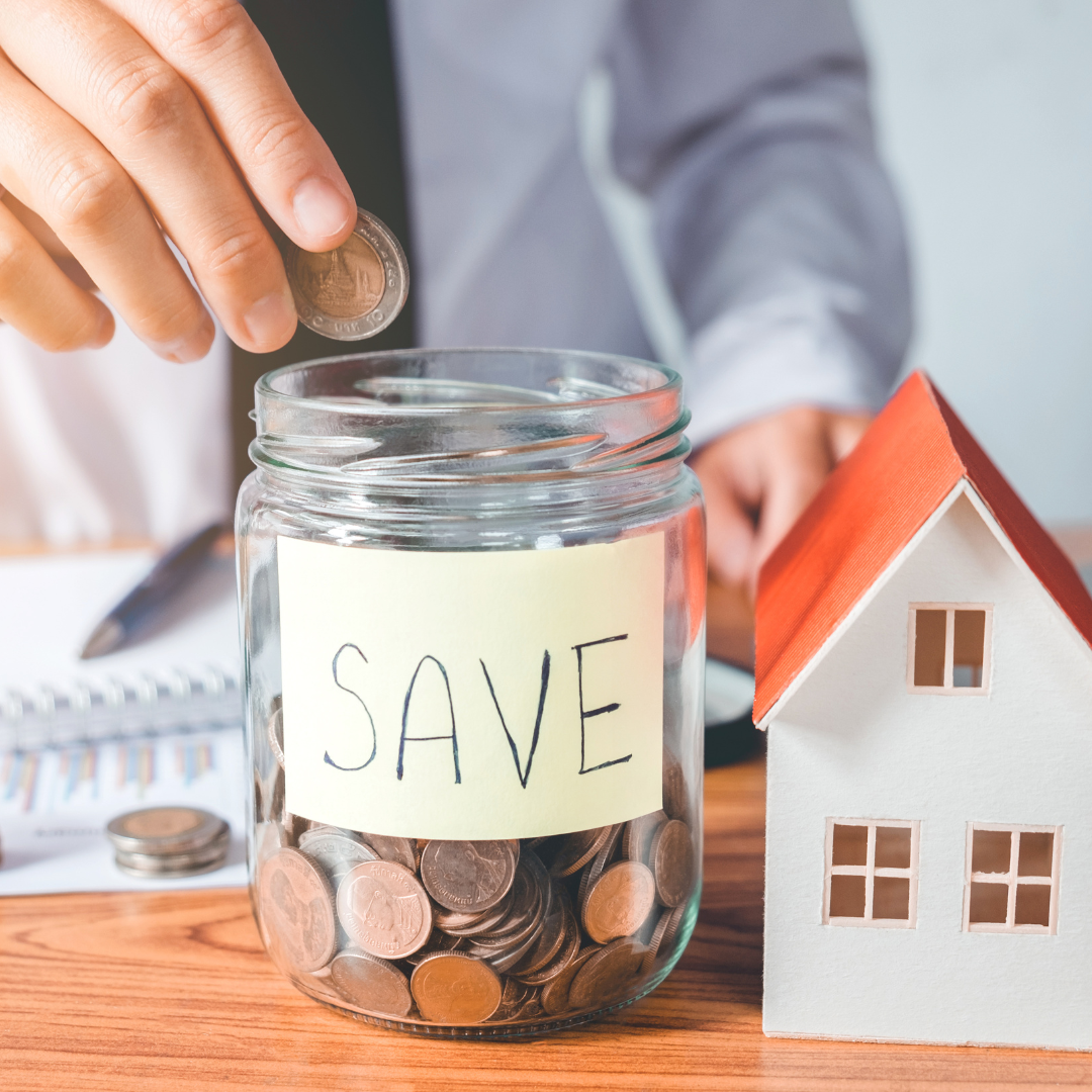 "Save" jar filled with coins next to a small house