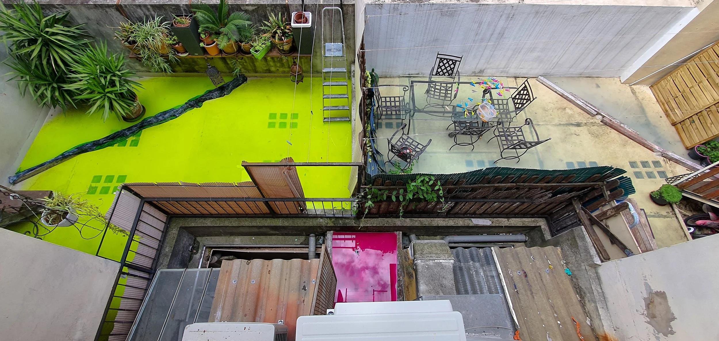 Balcon avec espace vert, plantes en pots, mobilier de jardin, espace de jeux pour enfants et éléments de décoration.