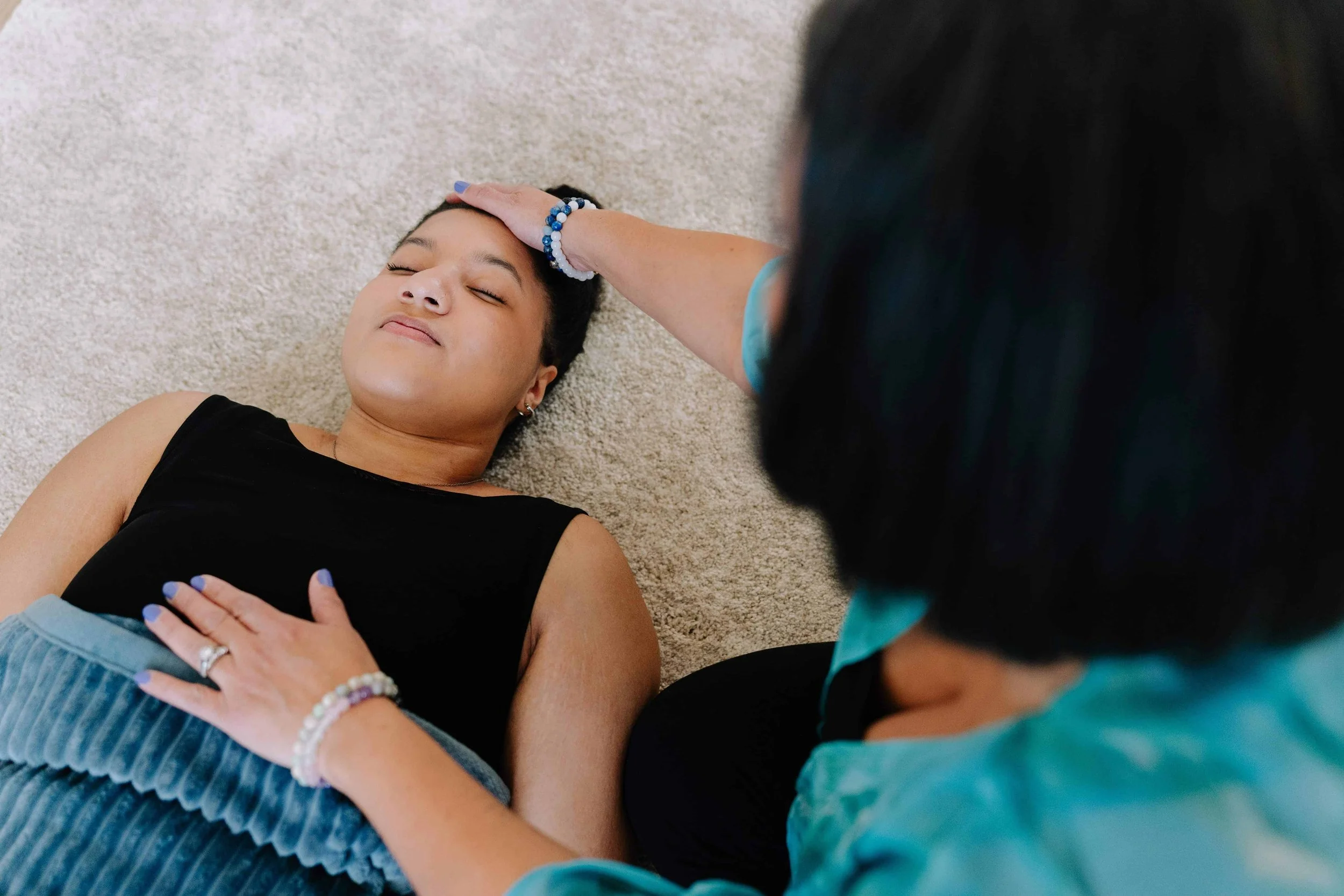 Energy healer with hand on client's forehead, client looks calm and relaxed.