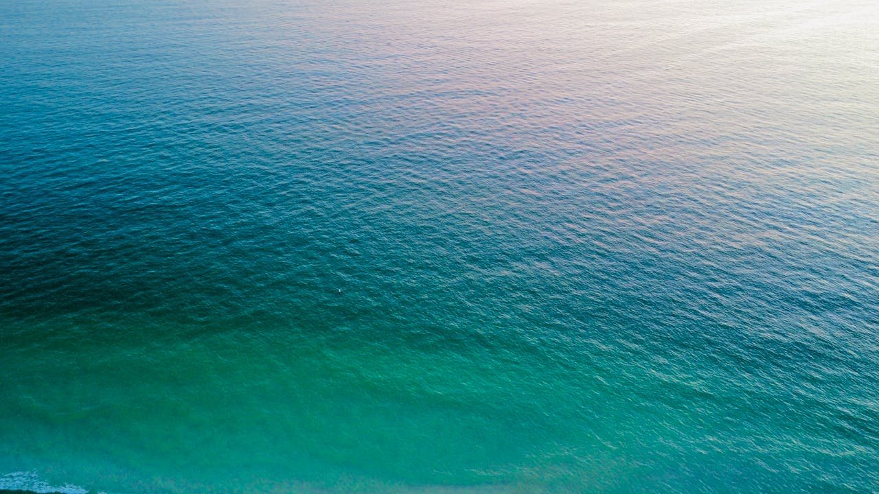 A calm ocean with gentle waves and a gradient of blue and green hues.