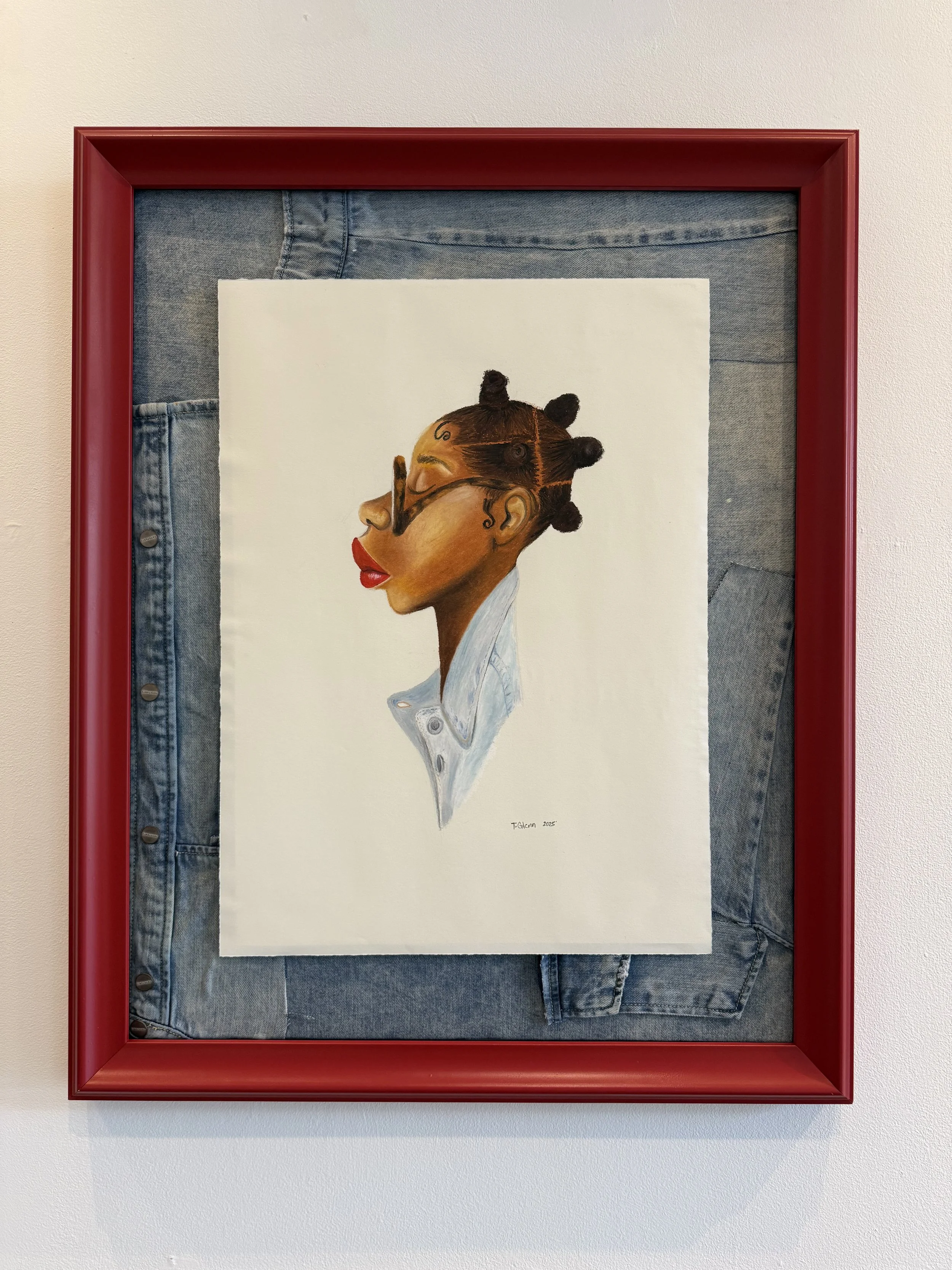 Artwork of a woman with her hair styled in Bantu knots, wearing glasses, red lipstick, and a white collared shirt, framed with denim fabric and a red border.