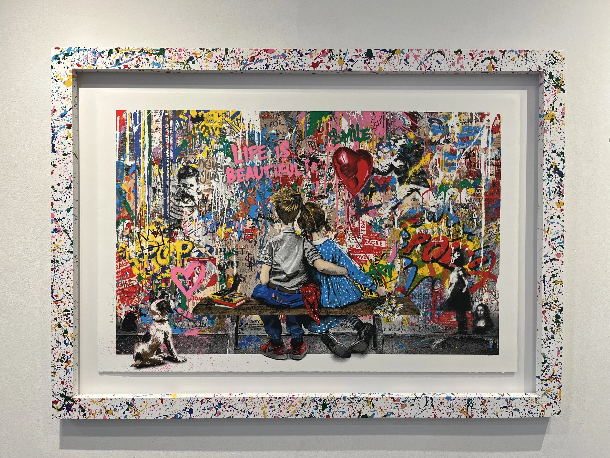 A colorful artwork depicting two children, a boy and a girl, sitting on a bench in front of a vibrant, graffiti-covered wall. The girl holds a heart-shaped balloon, and a dog is sitting nearby. The artwork has graffiti with words like 'Life is beauti