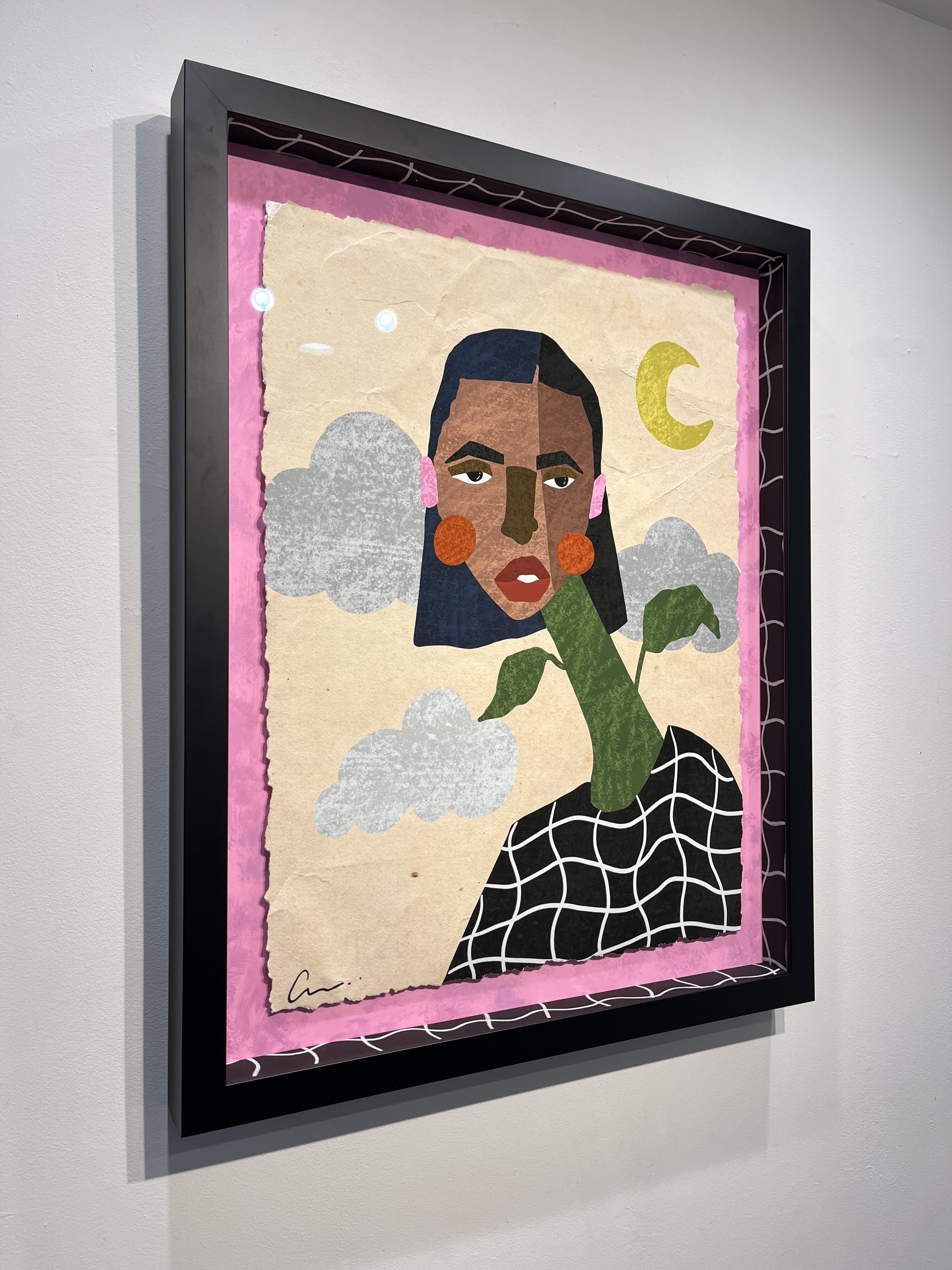 A framed artwork featuring a stylized portrait of a woman with dark hair, orange earrings, and pink earrings, against a background with clouds, a crescent moon, and abstract patterns.