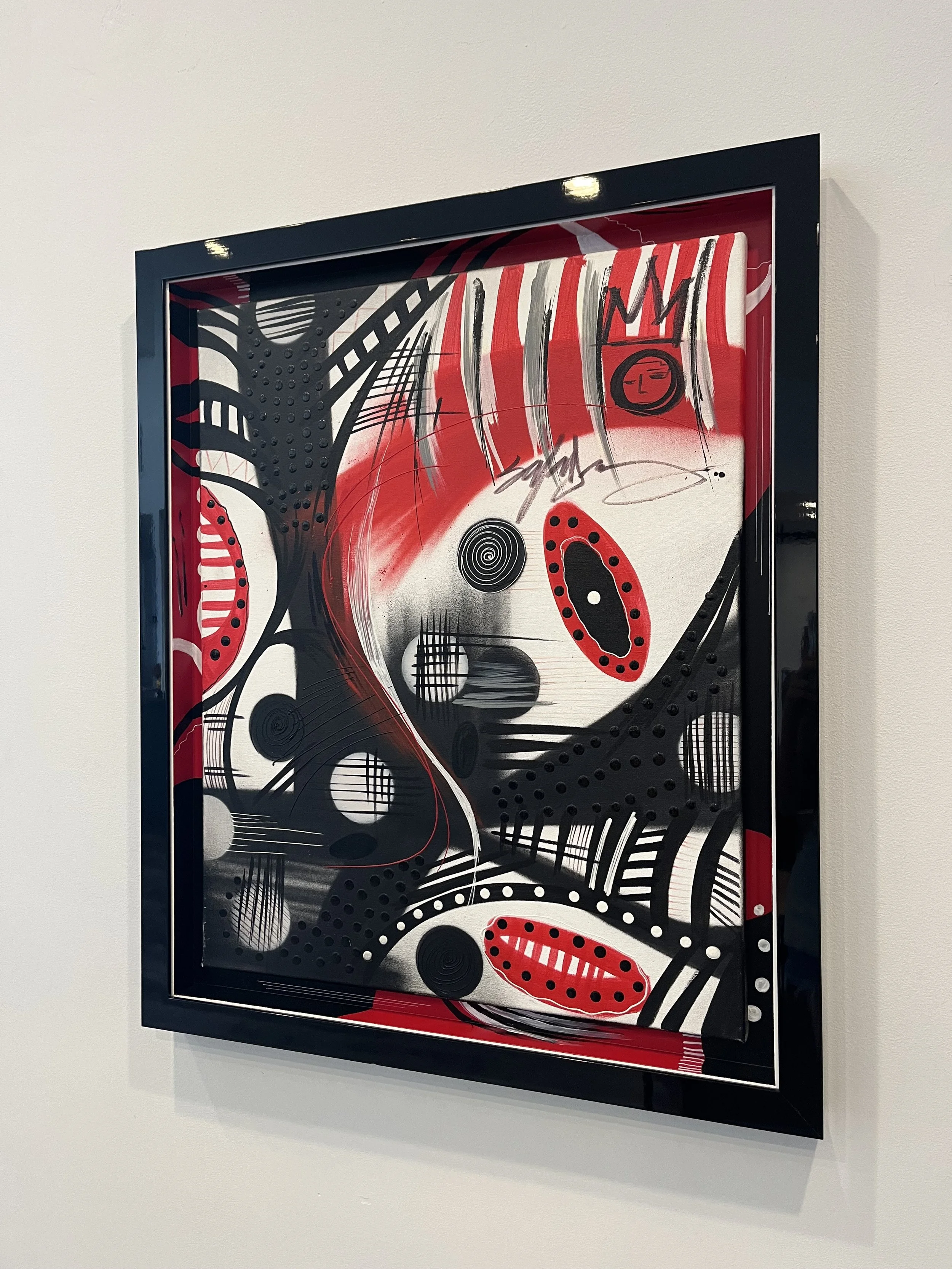 Abstract mixed media artwork featuring black, white, and red colors with patterns, spirals, dots, lines, and shapes in a black frame.