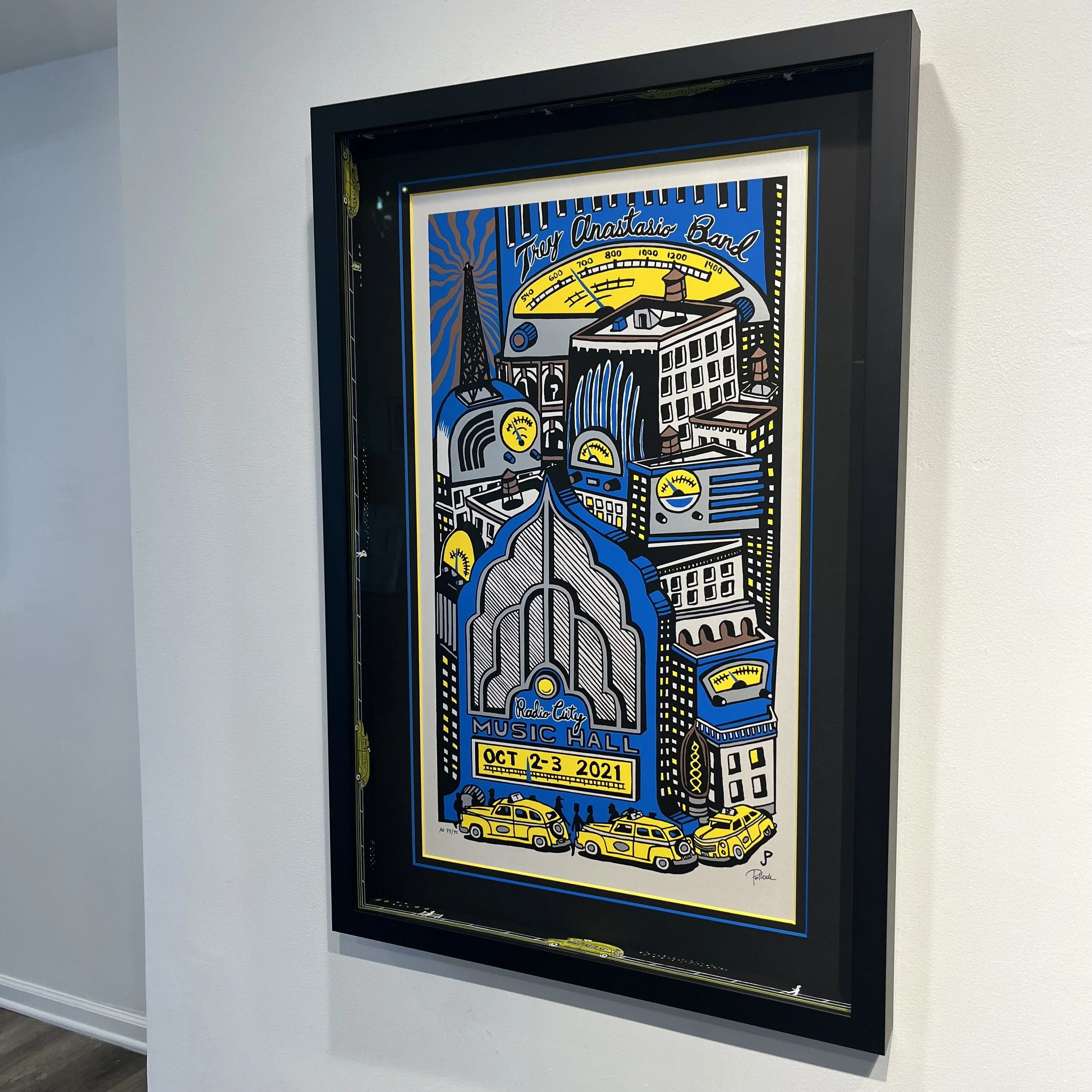 Colorful poster featuring a stylized cityscape with buildings, taxis, and people, promoting an event at Radio City Music Hall on October 2-3, 2021.