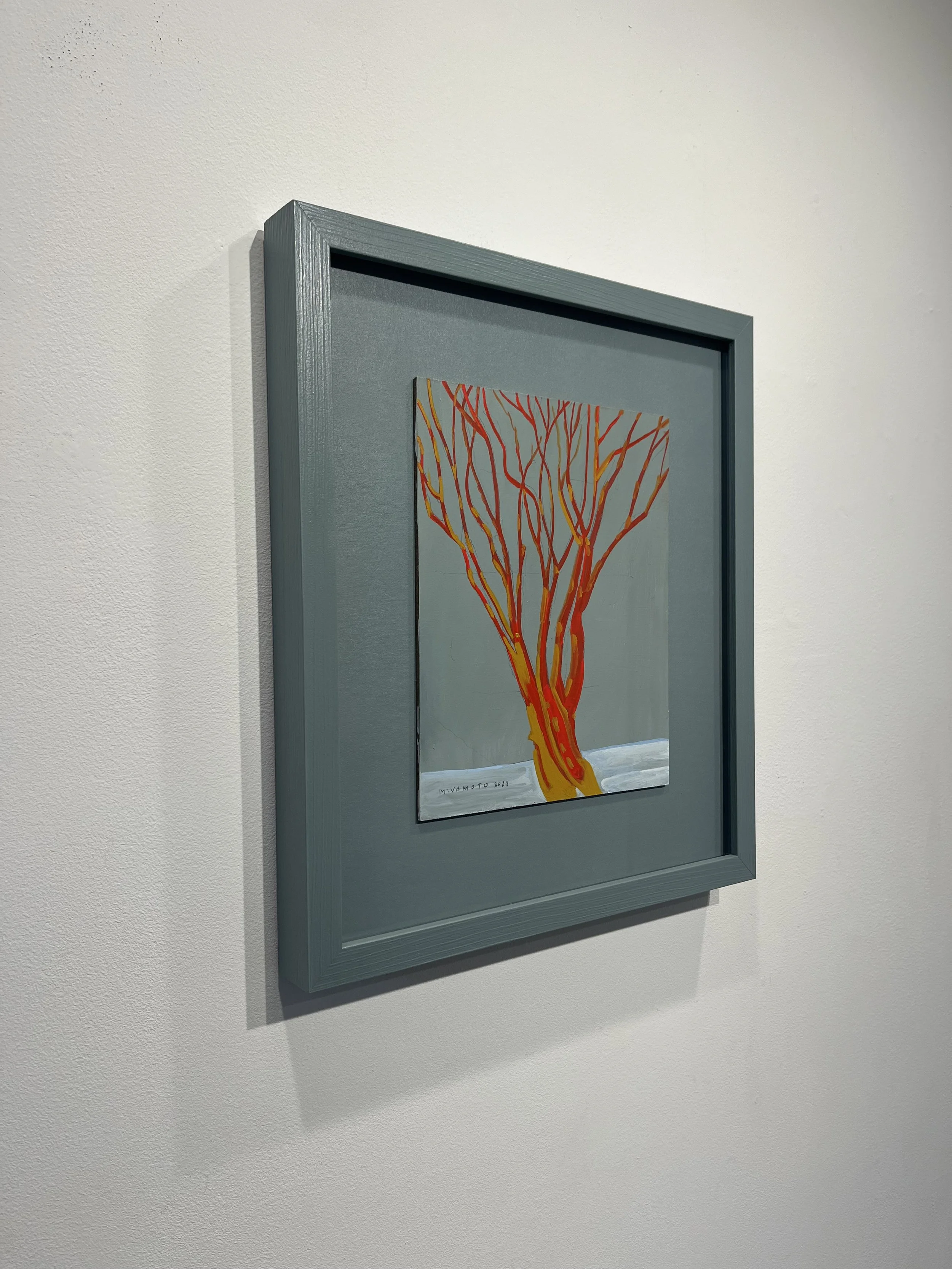 Painting of a stylized tree with orange and red branches against a pale blue background, framed and hung on a white wall.