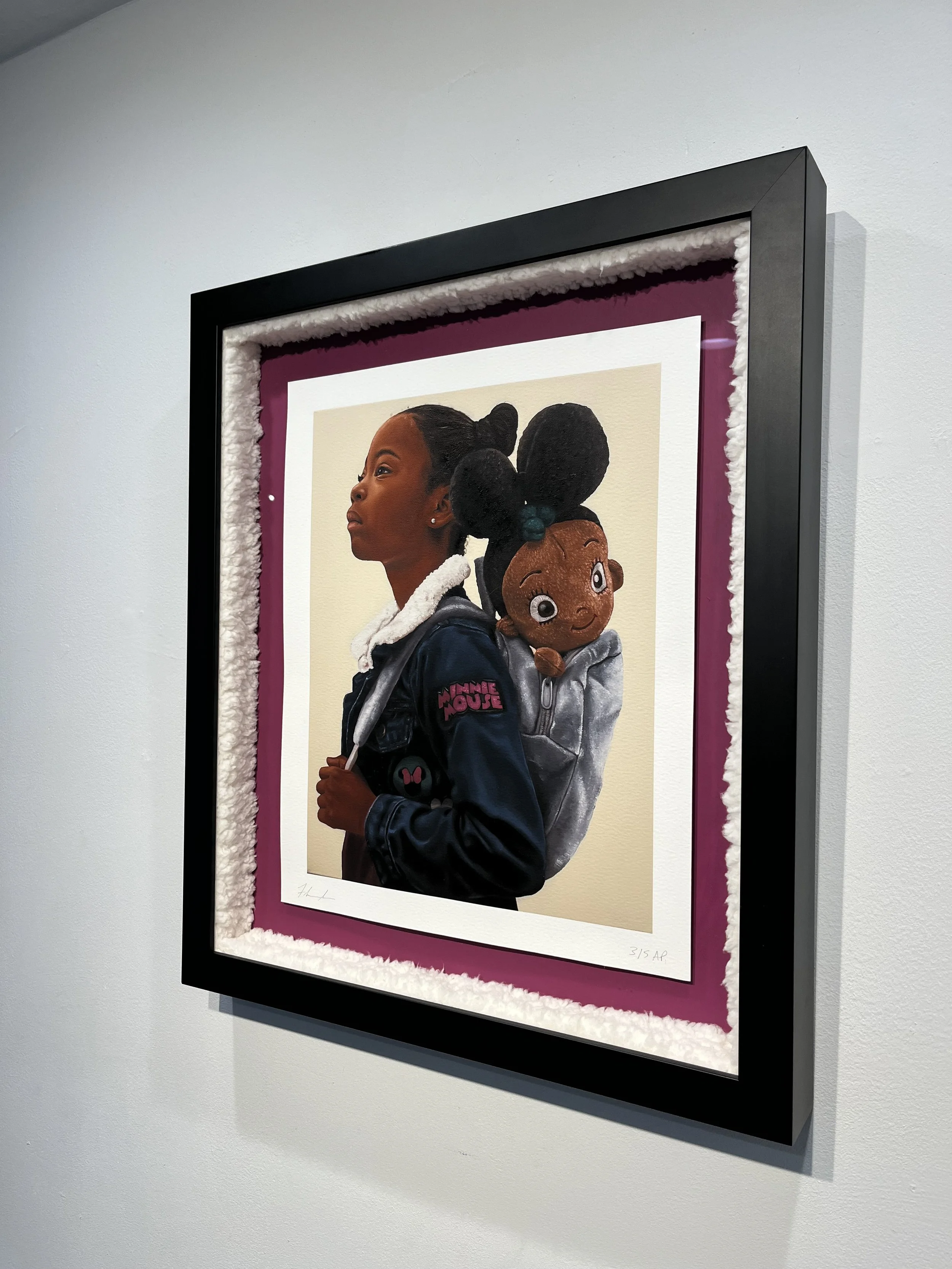 Art print of a young girl holding a plush doll, framed with black, white, and purple matting, displayed on a gallery wall.