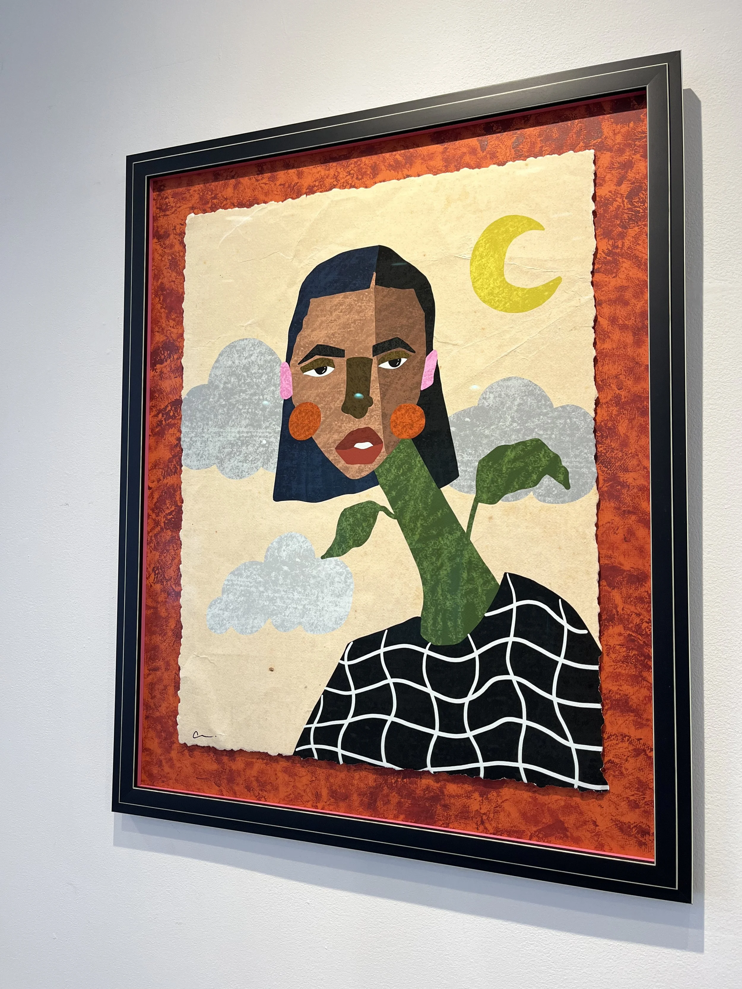Framed abstract artwork of a woman with dark hair, orange cheeks, pink earrings, and a plaid black and white top, with a green plant growing out of her neck, clouds, a yellow crescent moon, and yellow, pink, gray, and beige background elements.