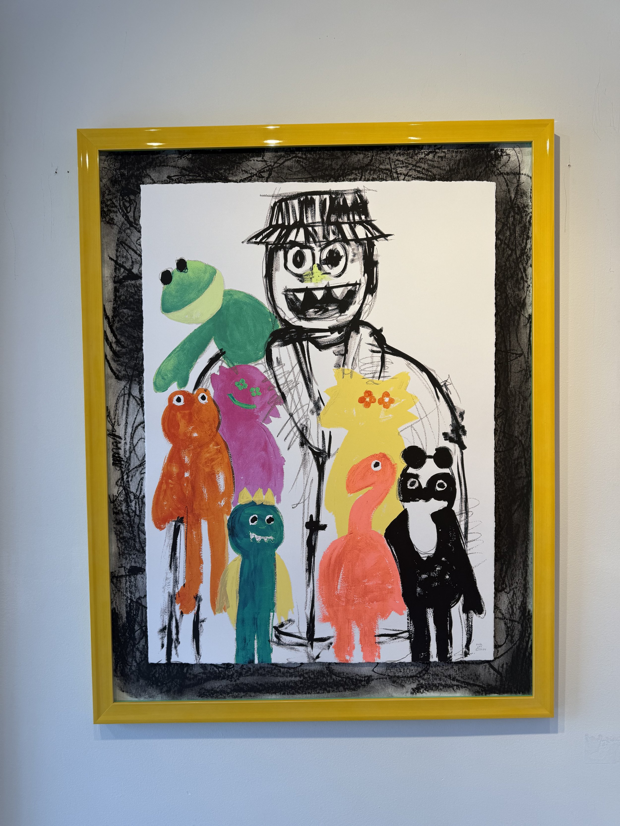 Colorful artwork of a smiling figure with a hat, surrounded by various cartoonish monster characters in bright colors, within a yellow frame.