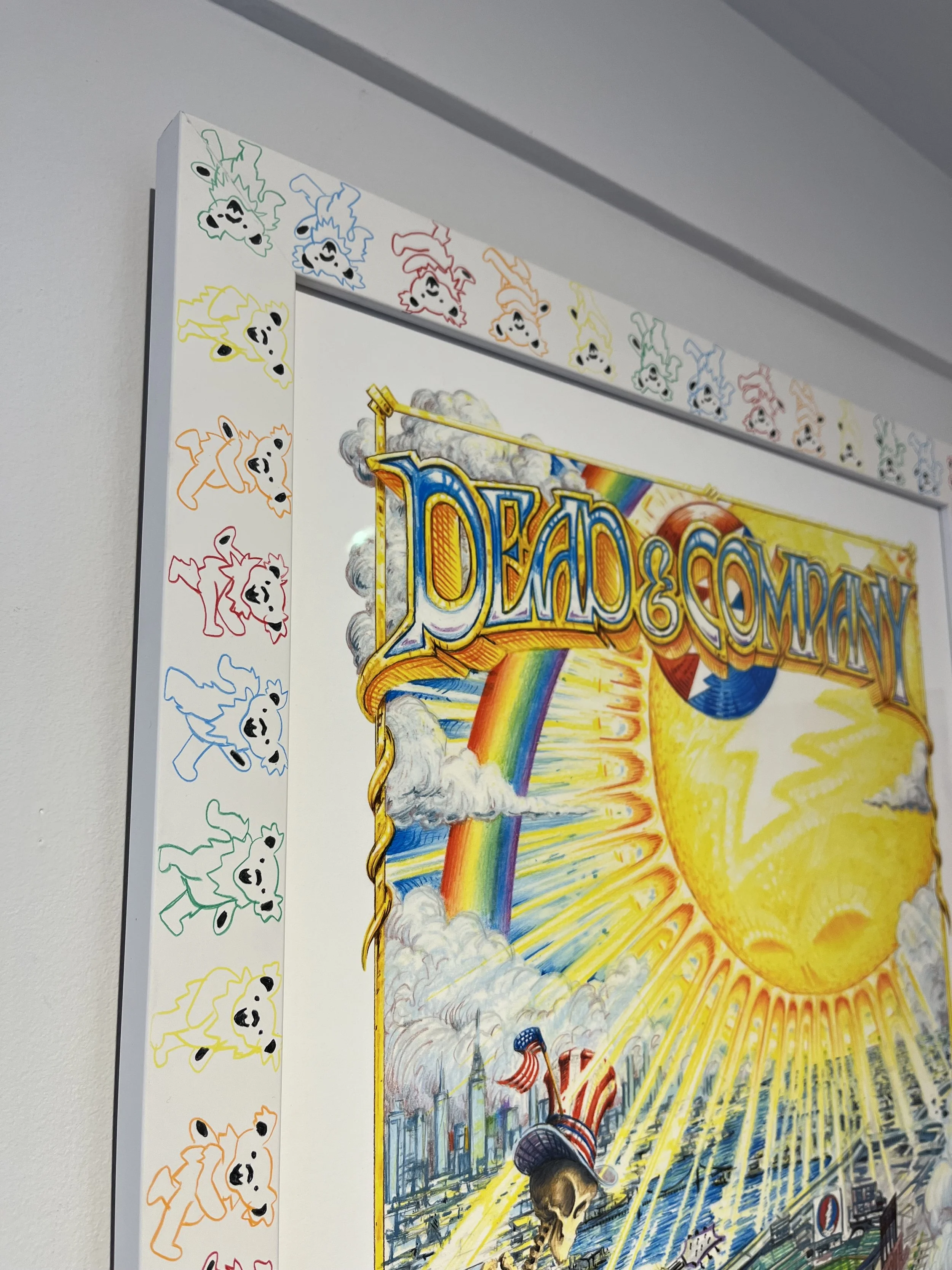 Colorful poster featuring a large yellow sun, rainbow, clouds, and a skeleton dressed as Uncle Sam playing a guitar in a cityscape.