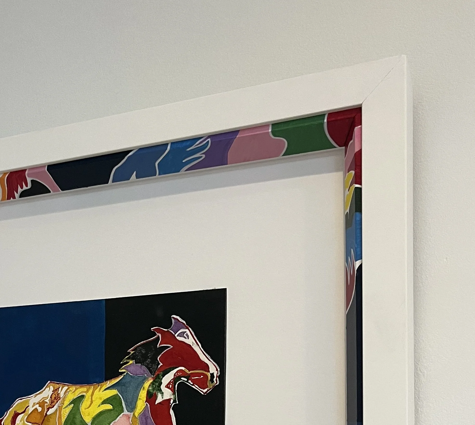 A colorful, abstract artwork on a wall featuring a stylized, multi-colored animal figure, possibly a wolf or dog, with bold lines and vibrant hues of red, yellow, green, purple, and black.