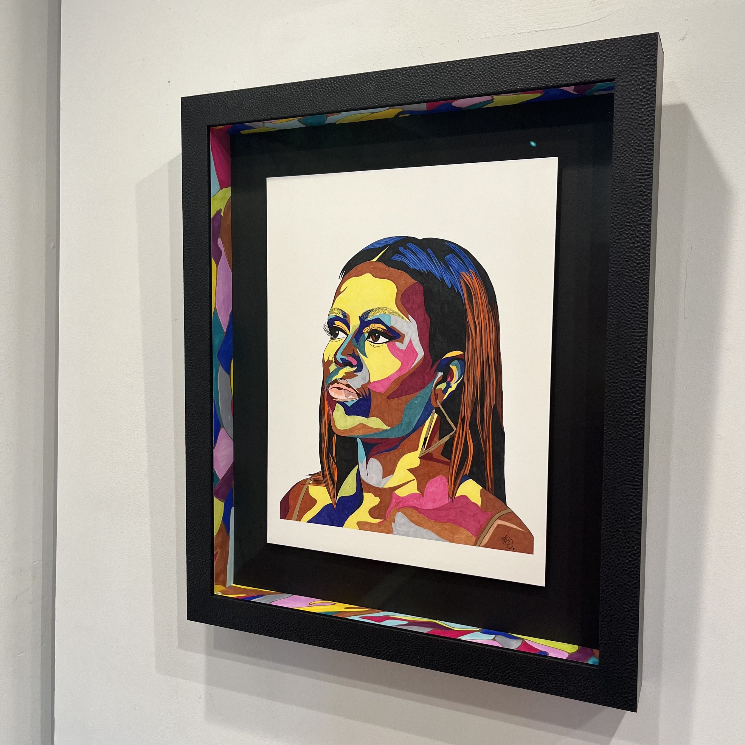 Colorful portrait of a woman with long hair, styled to the side, created with vibrant abstract shapes and hues, framed and hung on a white wall.