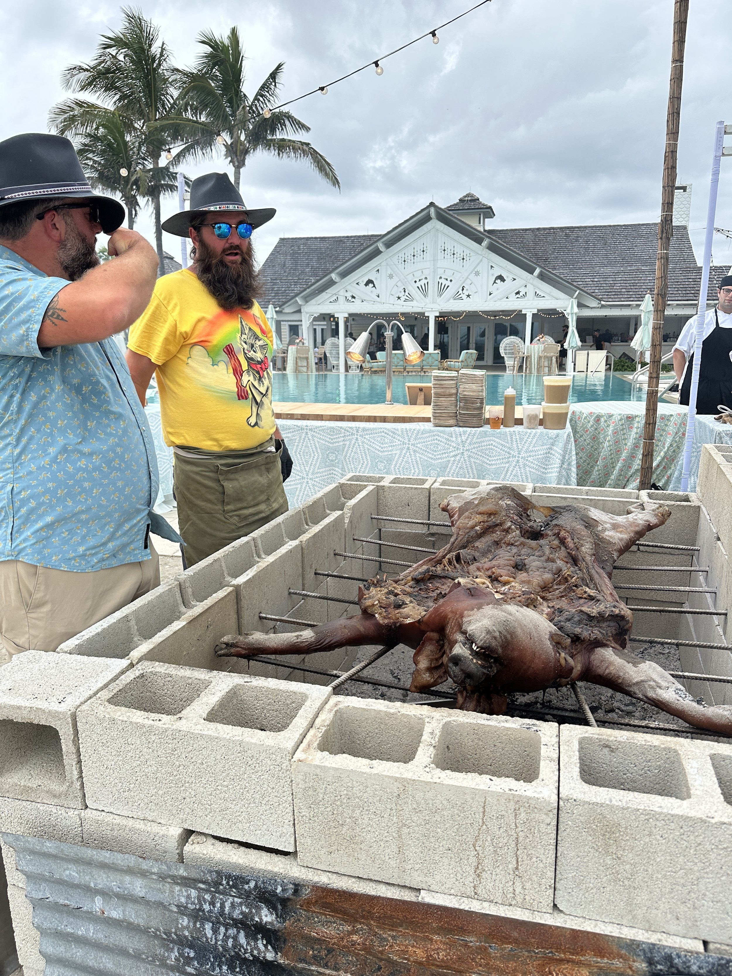 Chef Josh cooking at an outdoor pig roast near a beach.
