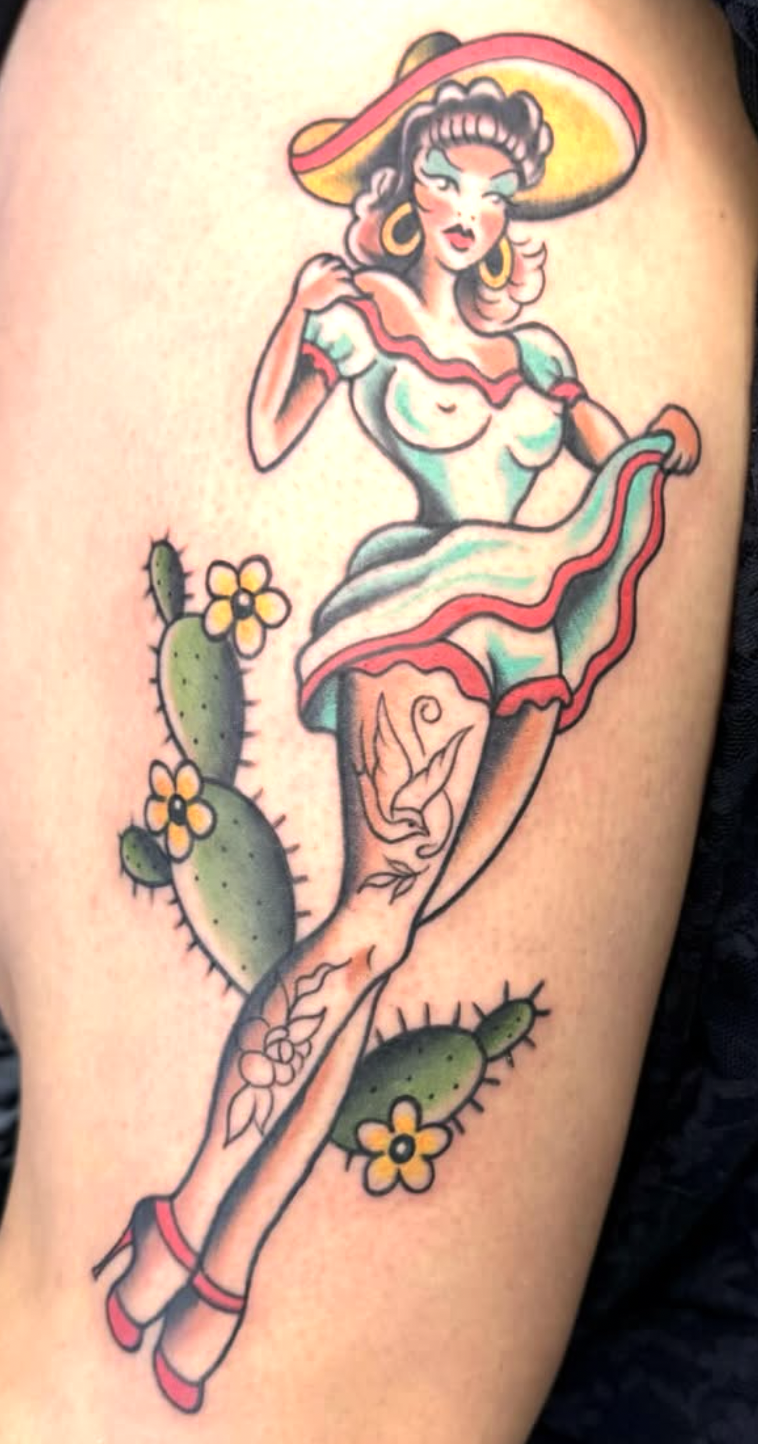 Tattoo of a woman in a traditional Mexican dress with a large sombrero, holding her skirt, surrounded by cacti with yellow flowers.