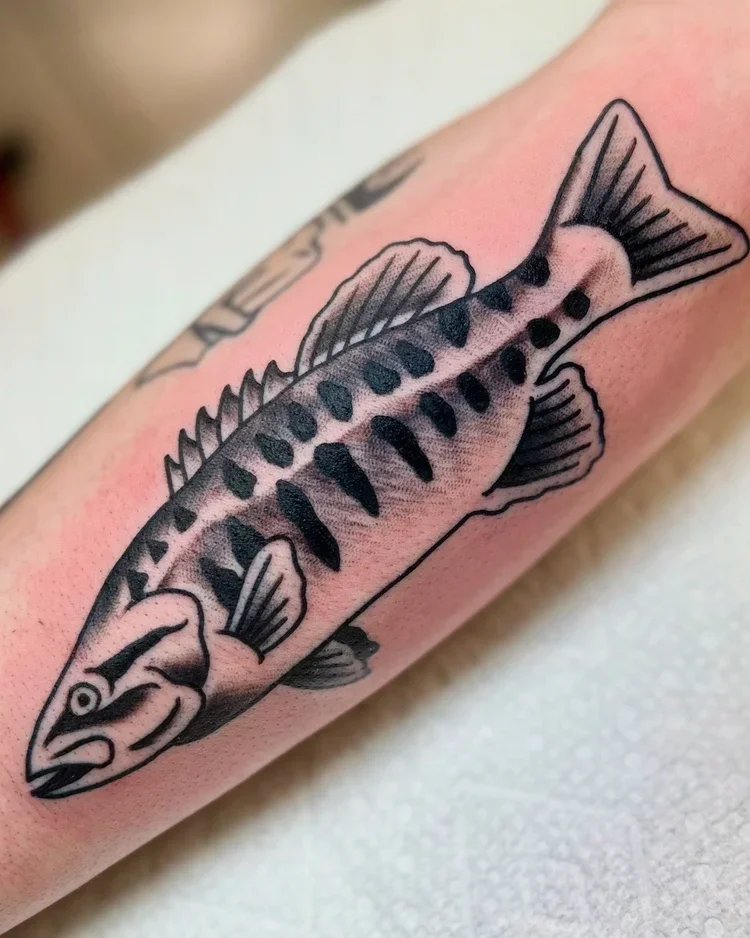 Tattoo of a fish with detailed fins and black spots on the skin.