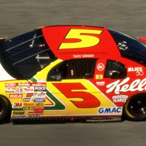A red and black race car with the number 5 on the hood and side, featuring various sponsor logos and the name Tommy Baldwin.