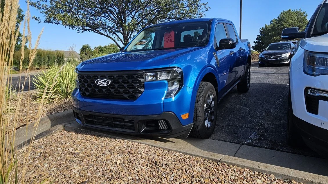 A blue 2025 Ford Maverick sits in the Quantum Credit Union parking lot.