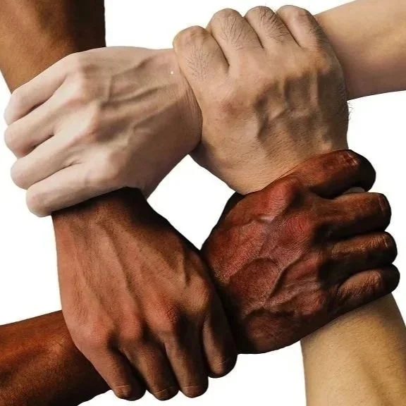Four hands, each with different skin tones, clasped together in a circle.