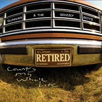 A vintage car with a retired license plate, displaying a message beneath the bumper that reads, 'Came to work while alive.'