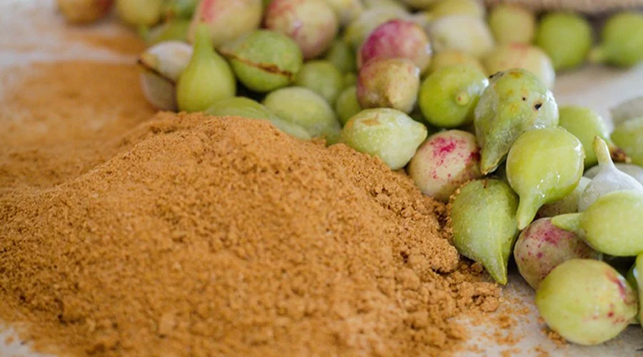 Fresh green and purple Indian gooseberries next to ground powder.