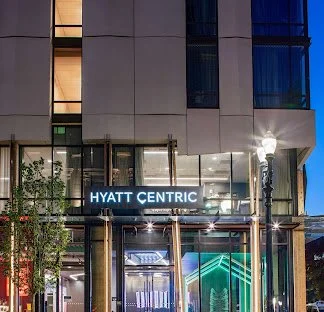 Nighttime city street scene with a Hyatt Centric hotel sign and illuminated building facade