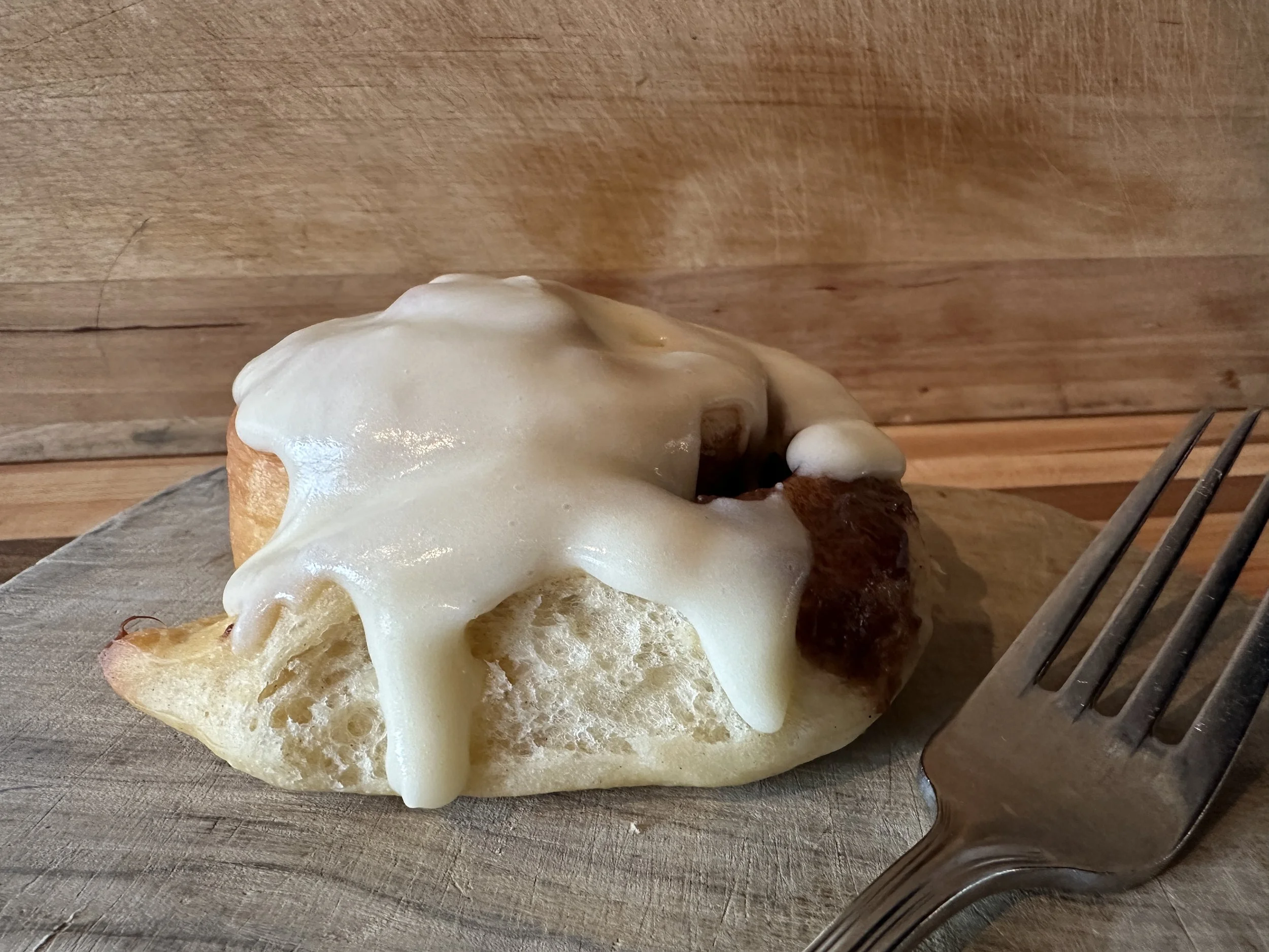 Biscuits topped with melted cheese on a wooden cutting board, with a fork nearby.