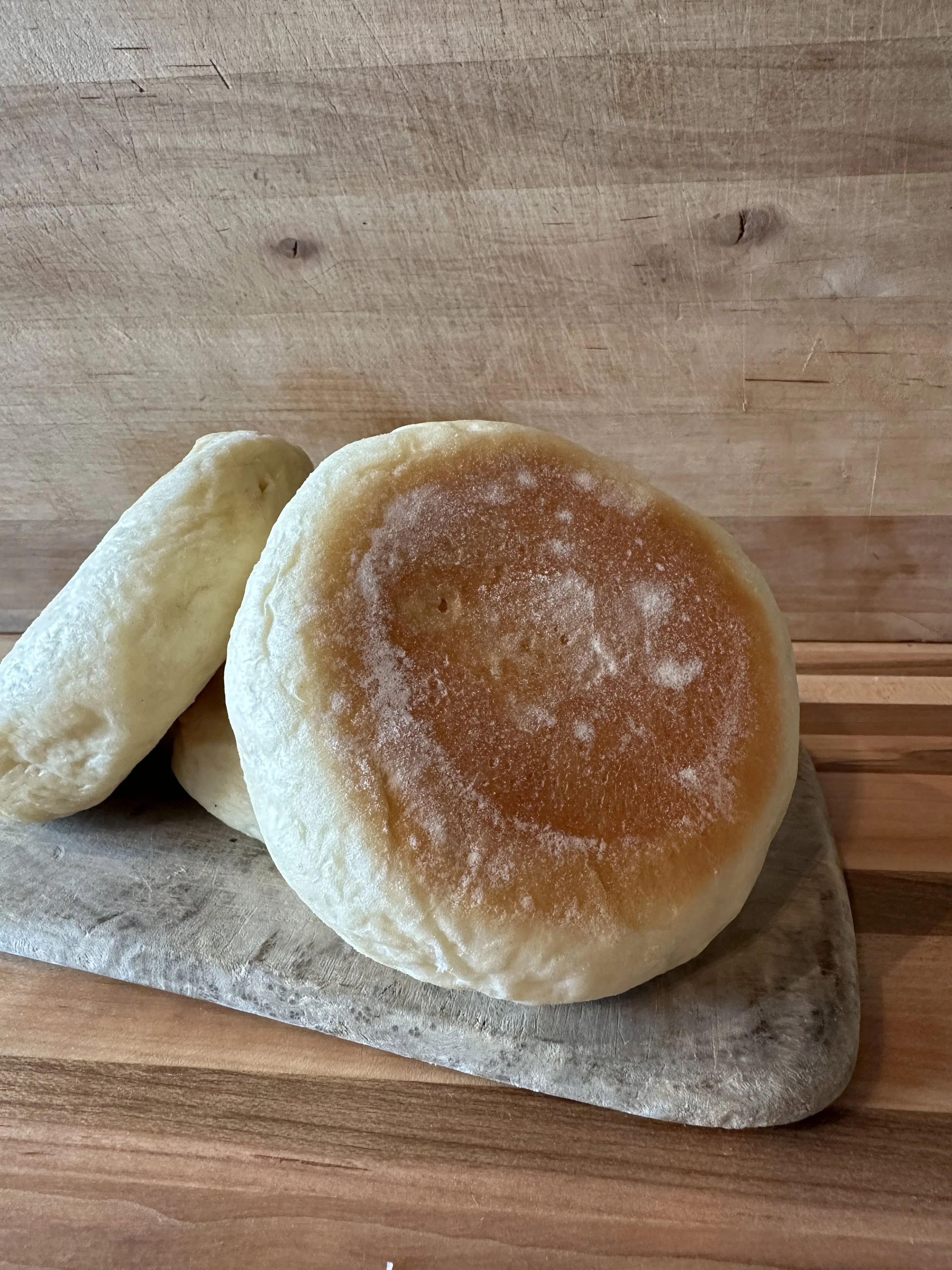 Three bread rolls, one with a golden-brown top, on a wooden surface