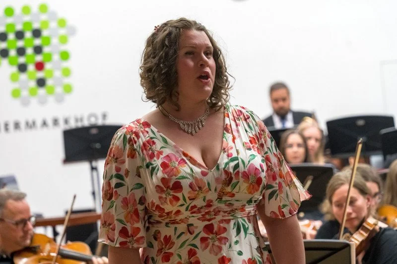 Sara Lynn Hargrave (Soprano) singing in front of an orchestra during a performance with the Johann Josef Fux orchestra.