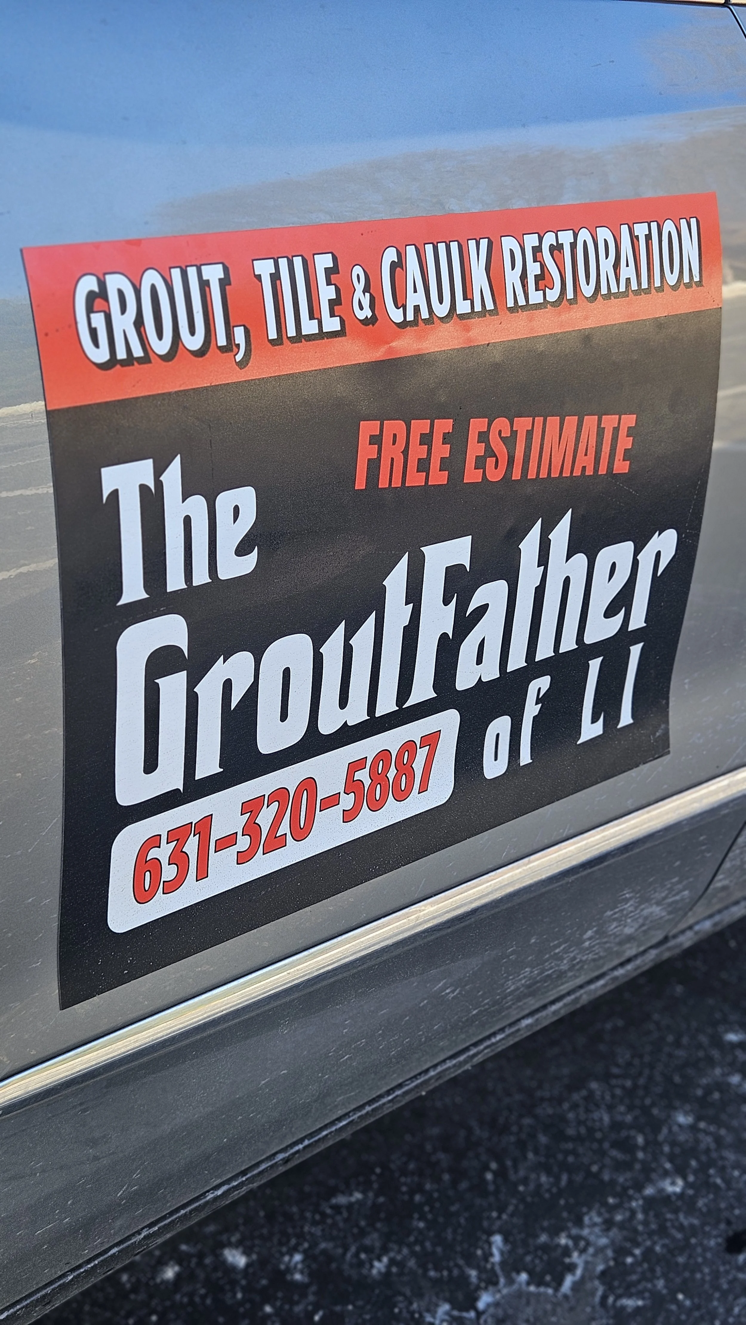 Sign on vehicle advertising grout, tile, and caulk restoration services, offering free estimate, with contact number 631-320-5887.