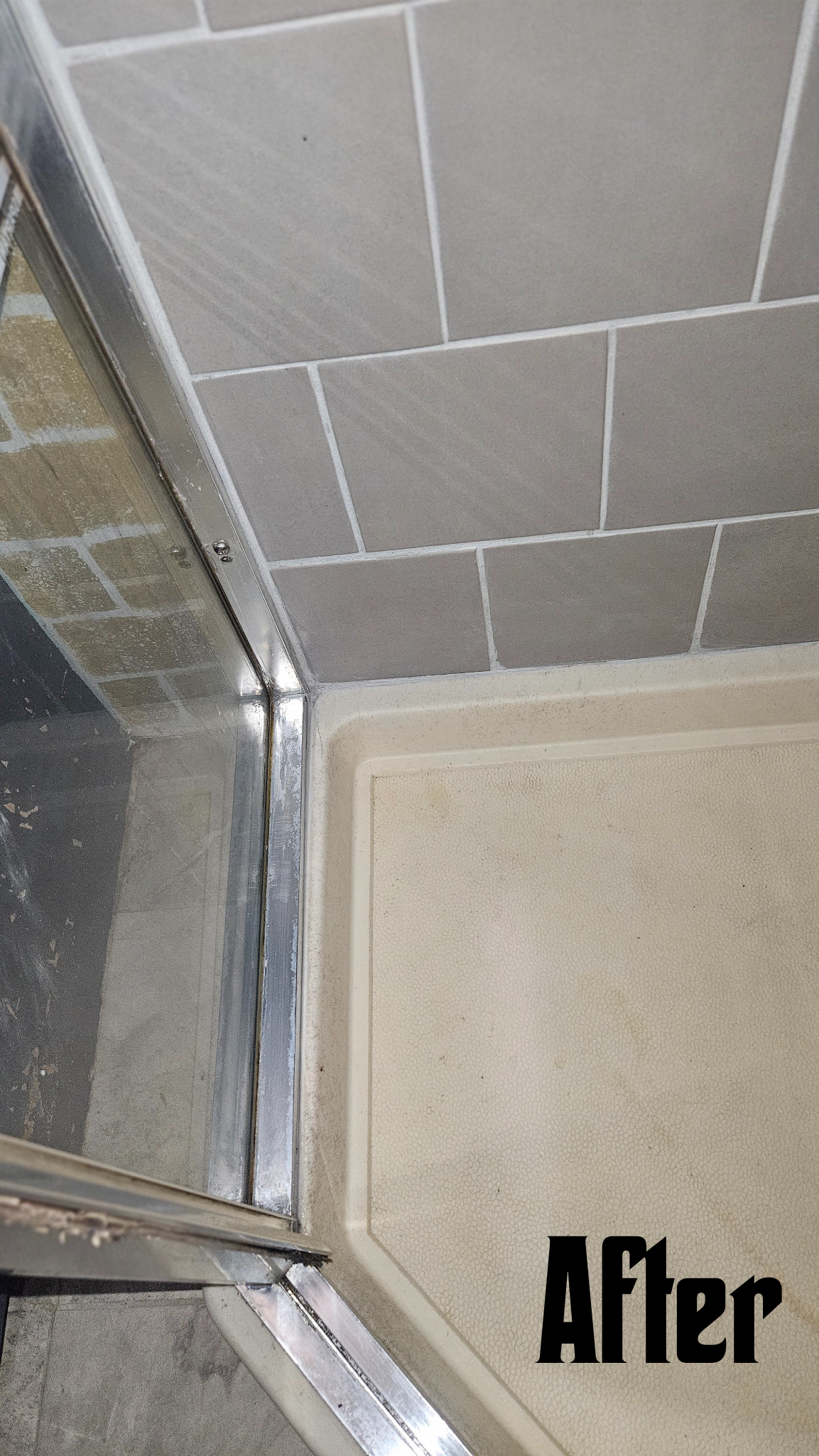 Close-up of a shower corner with new grey tiles, a metal shower door frame, and a textured shower base. The word "After" is written in black in the bottom right corner.