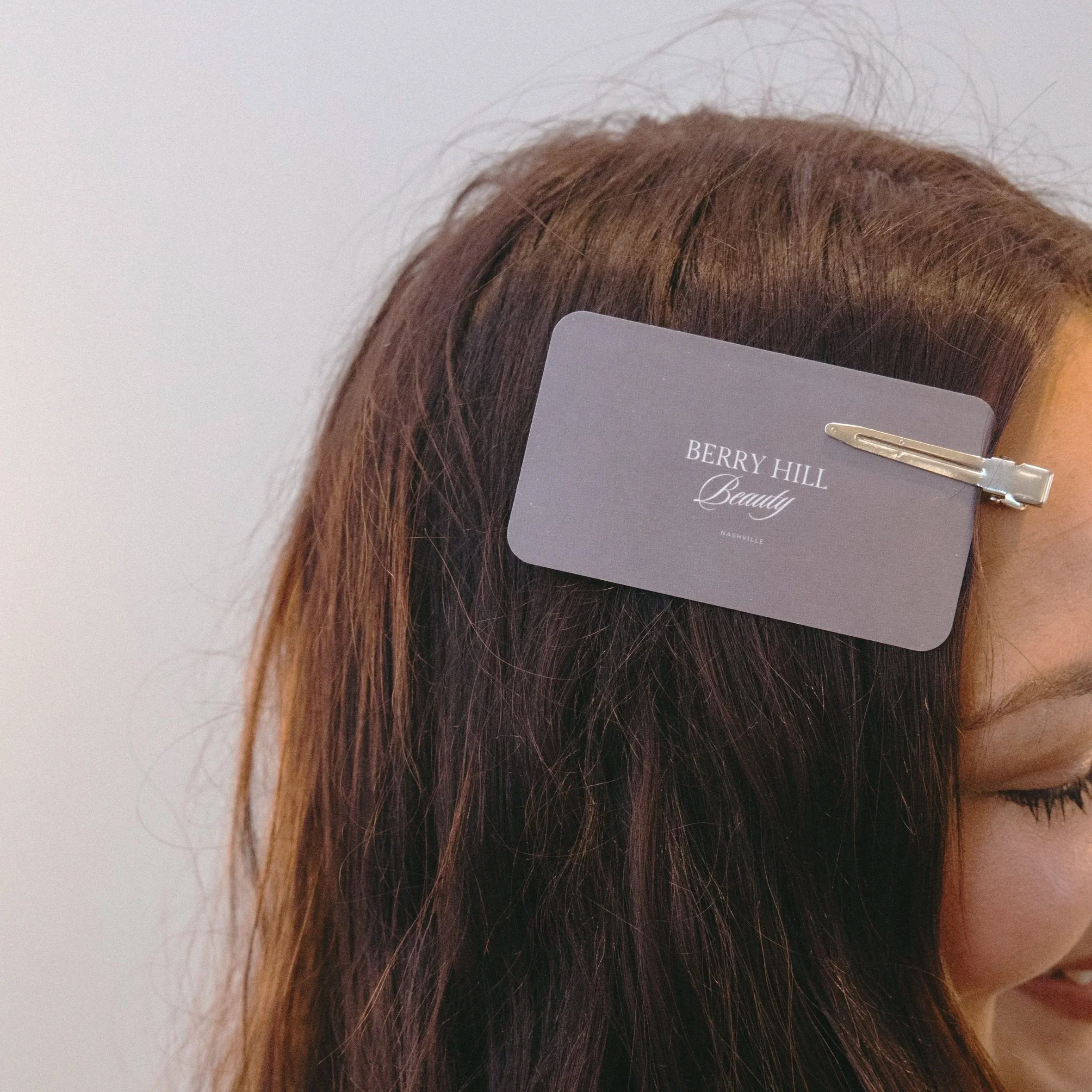 Close-up of reddish-brown hair with a gray tag that reads "BERRY HILL Beauty Nashville."