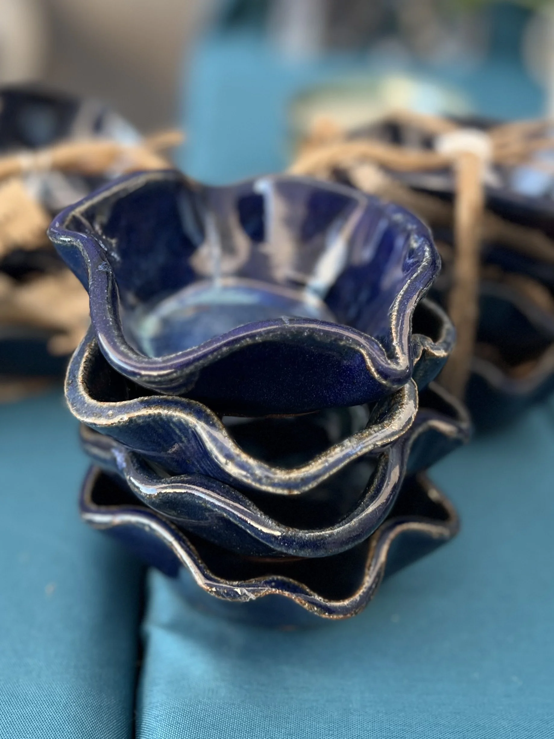 Stacked blue and black ceramic flower-shaped bowls on a teal surface.